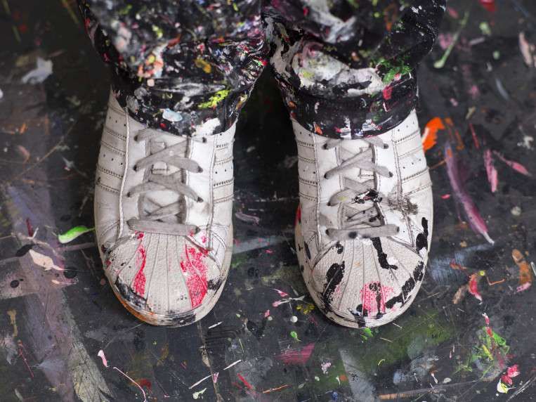 Witte schoenen onder de verfspetters