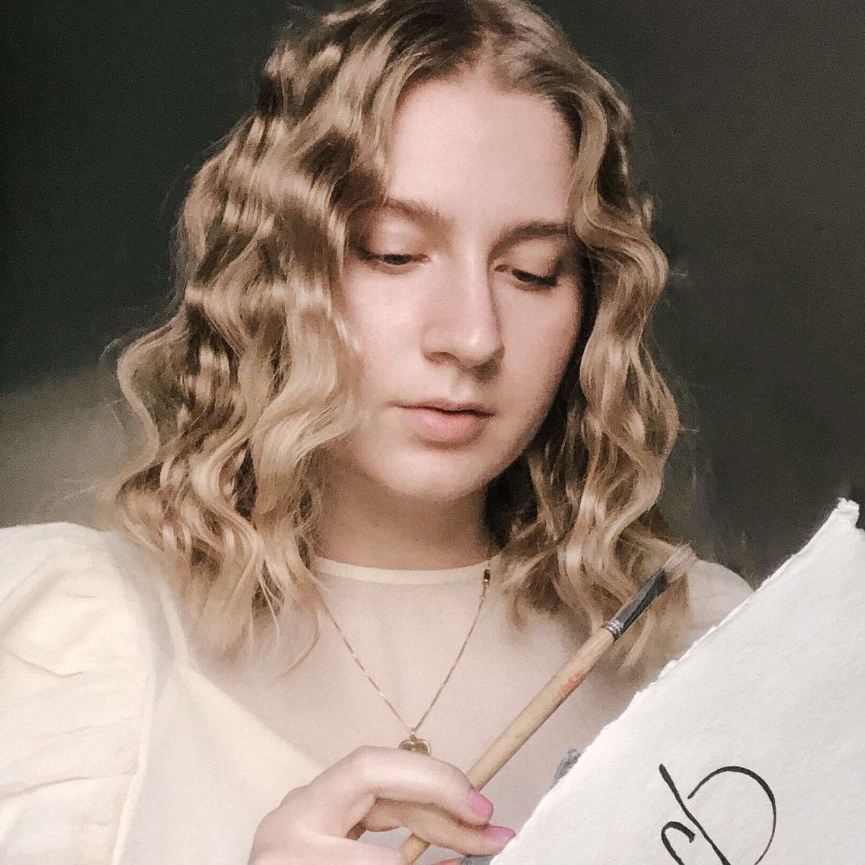 vrouw met blond haar heeft papier en kwast vast