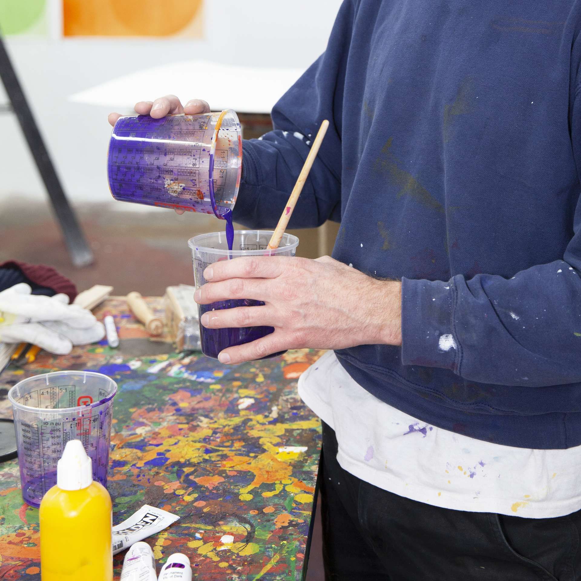 man giet blauwe verf over in een pot met kwast