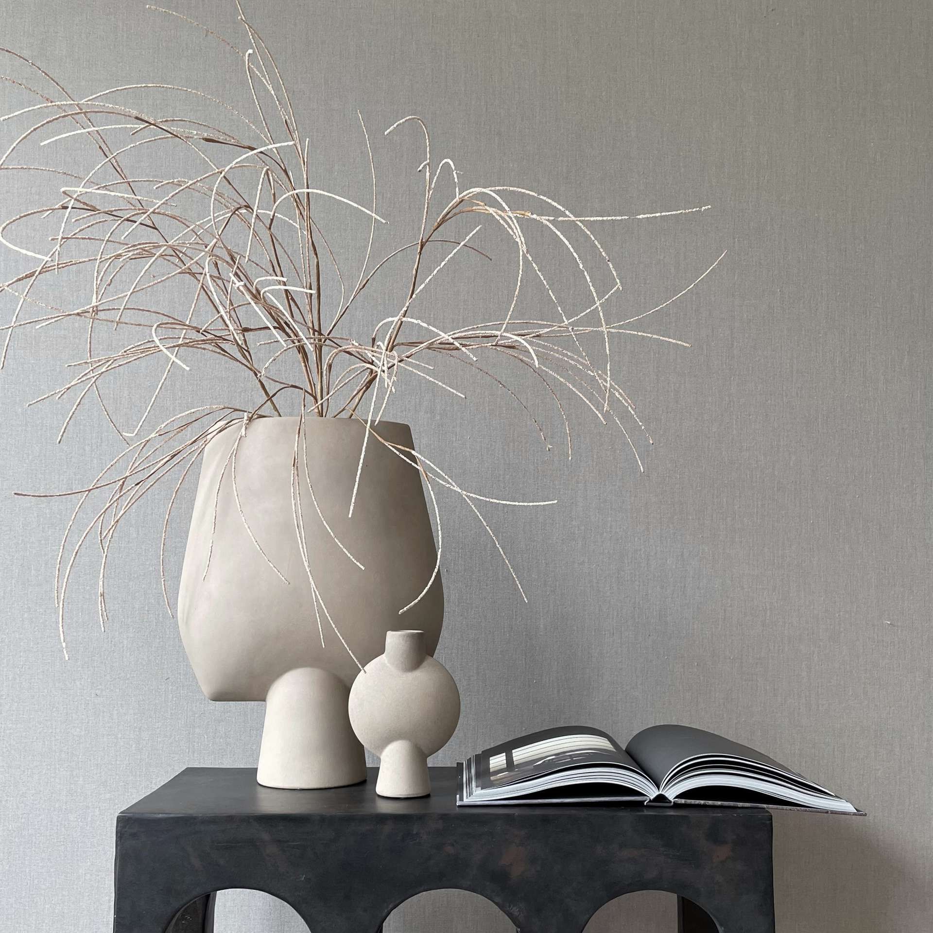 Zwart dressoir met beige vazen en koffietafelboek