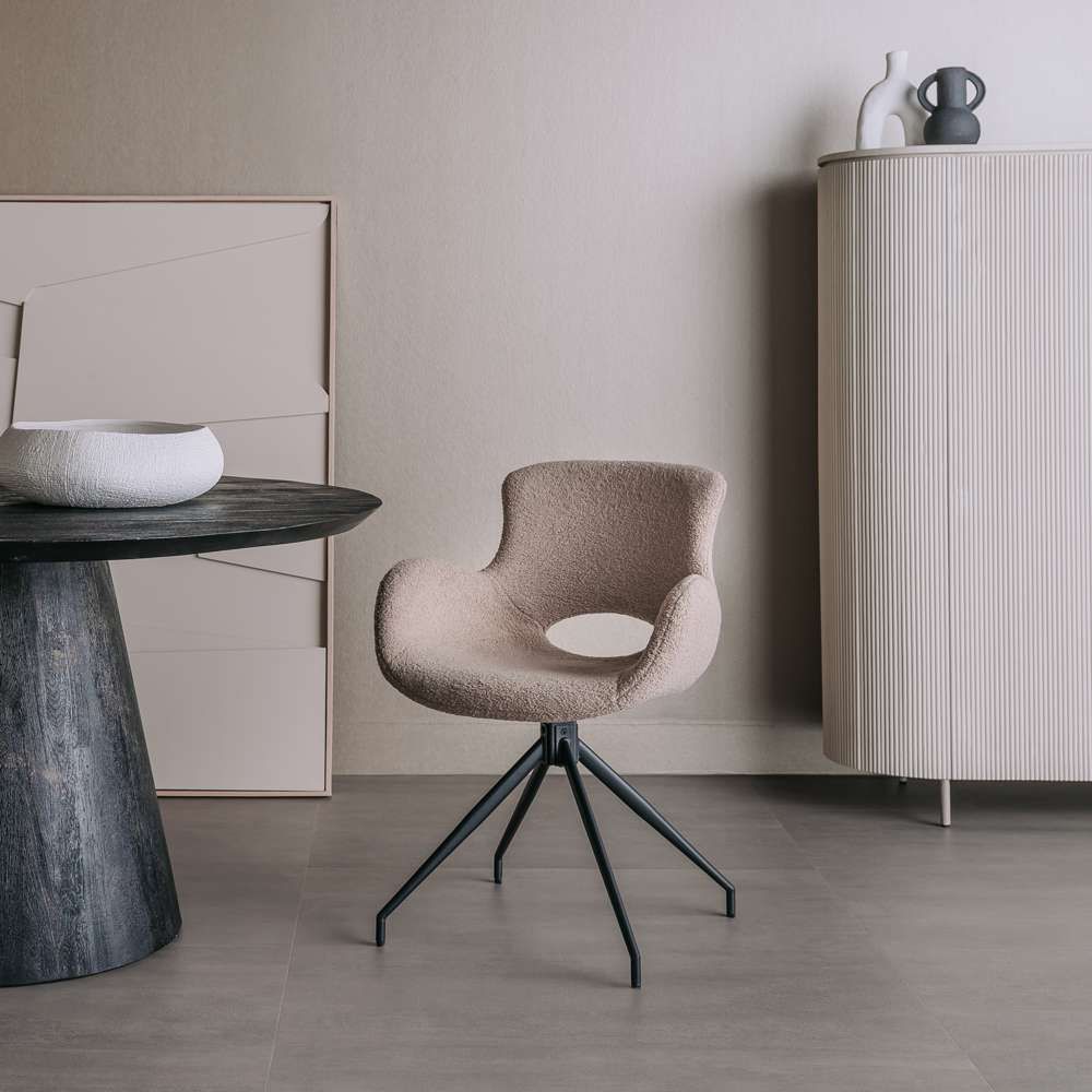 Beige stoel aan een ronde zwarte eettafel