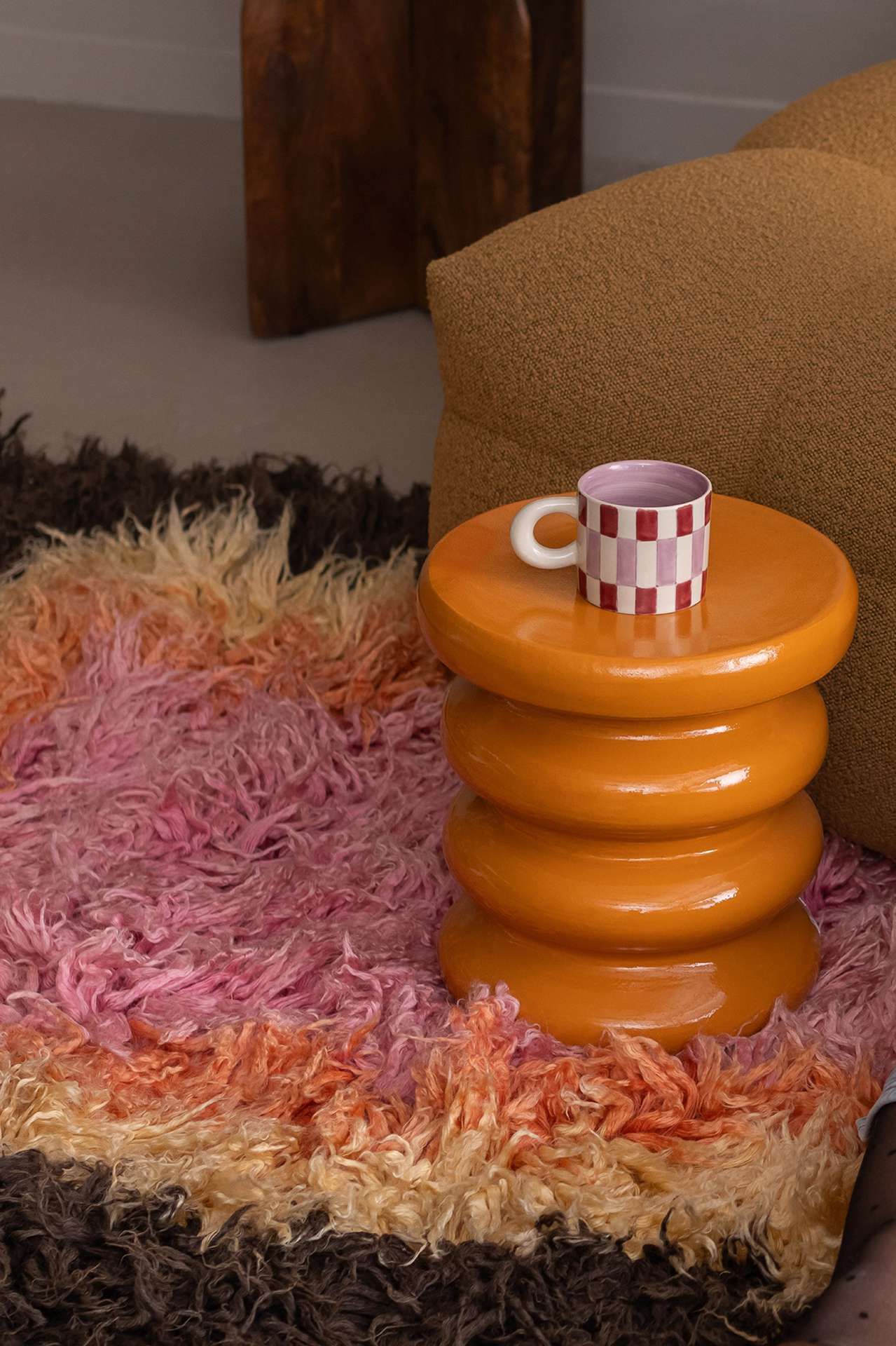 Oranje bijzettafeltje op een harig kleurrijk kleed