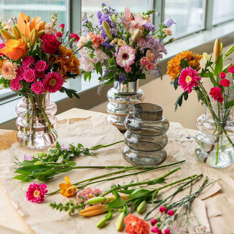 verschillende vazen met boeketten en losse bloemen op tafel