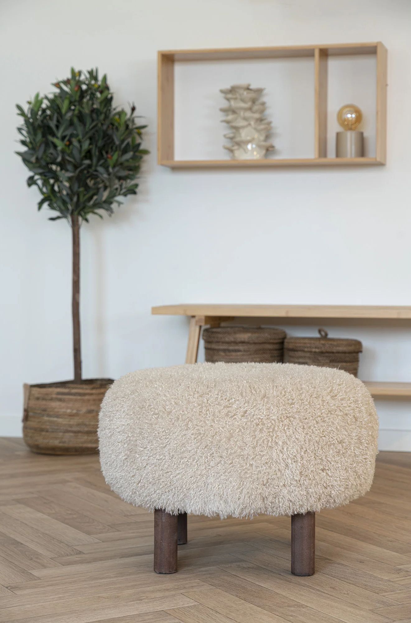 Fluffy beige poef met donker houten poten in woonruimte