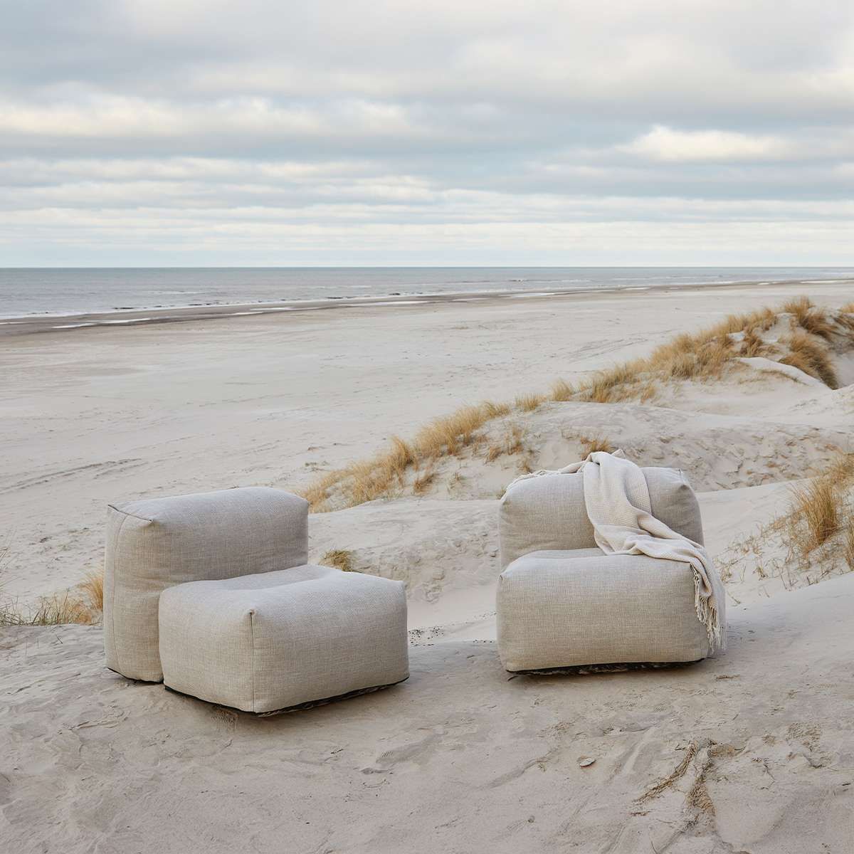 Twee beige fauteuils op het strand met een kleedje