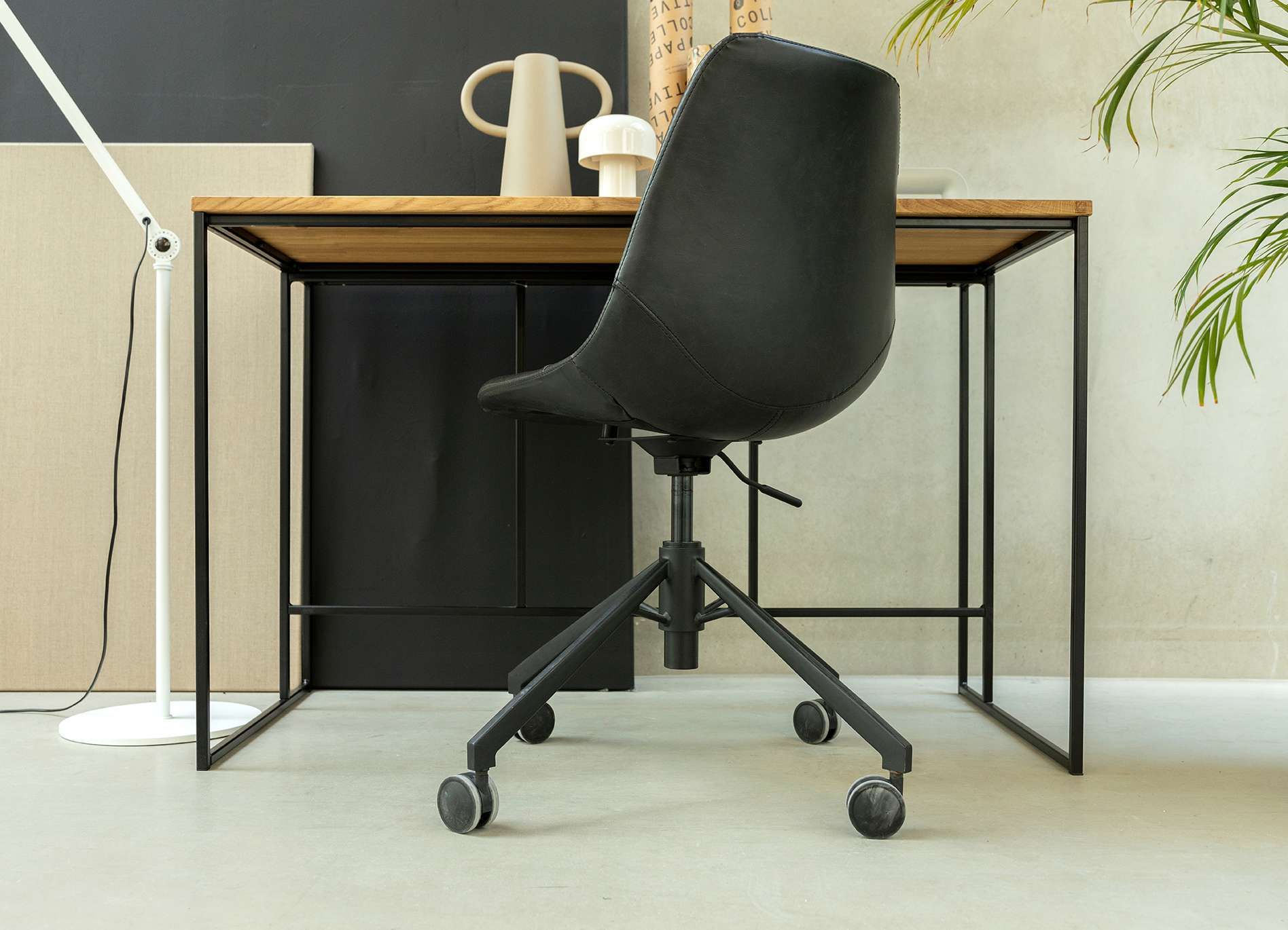 Zwarte bureaustoel met wieltjes bij een bureau