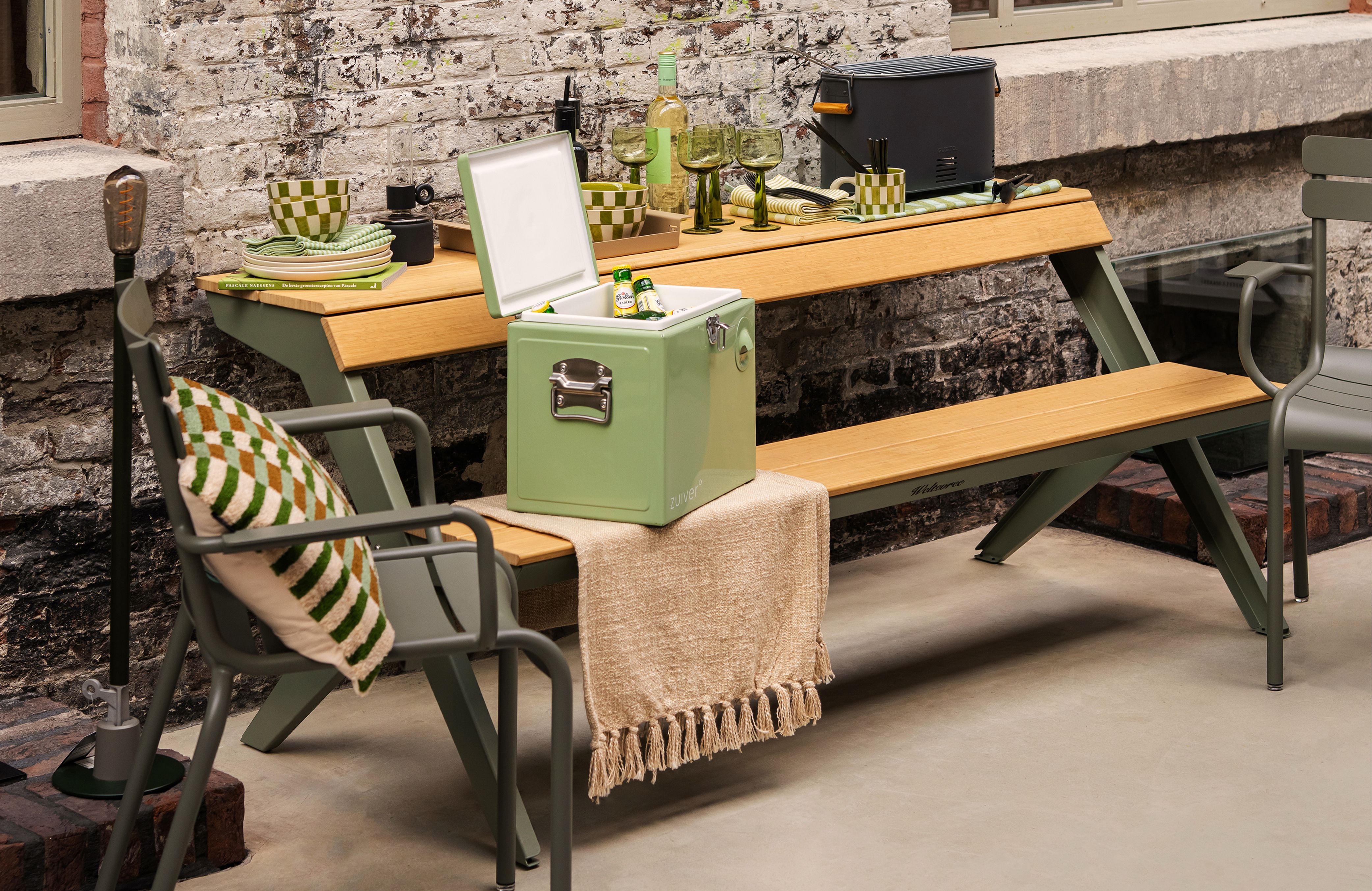 picknicktafel met servies en een koeler erop