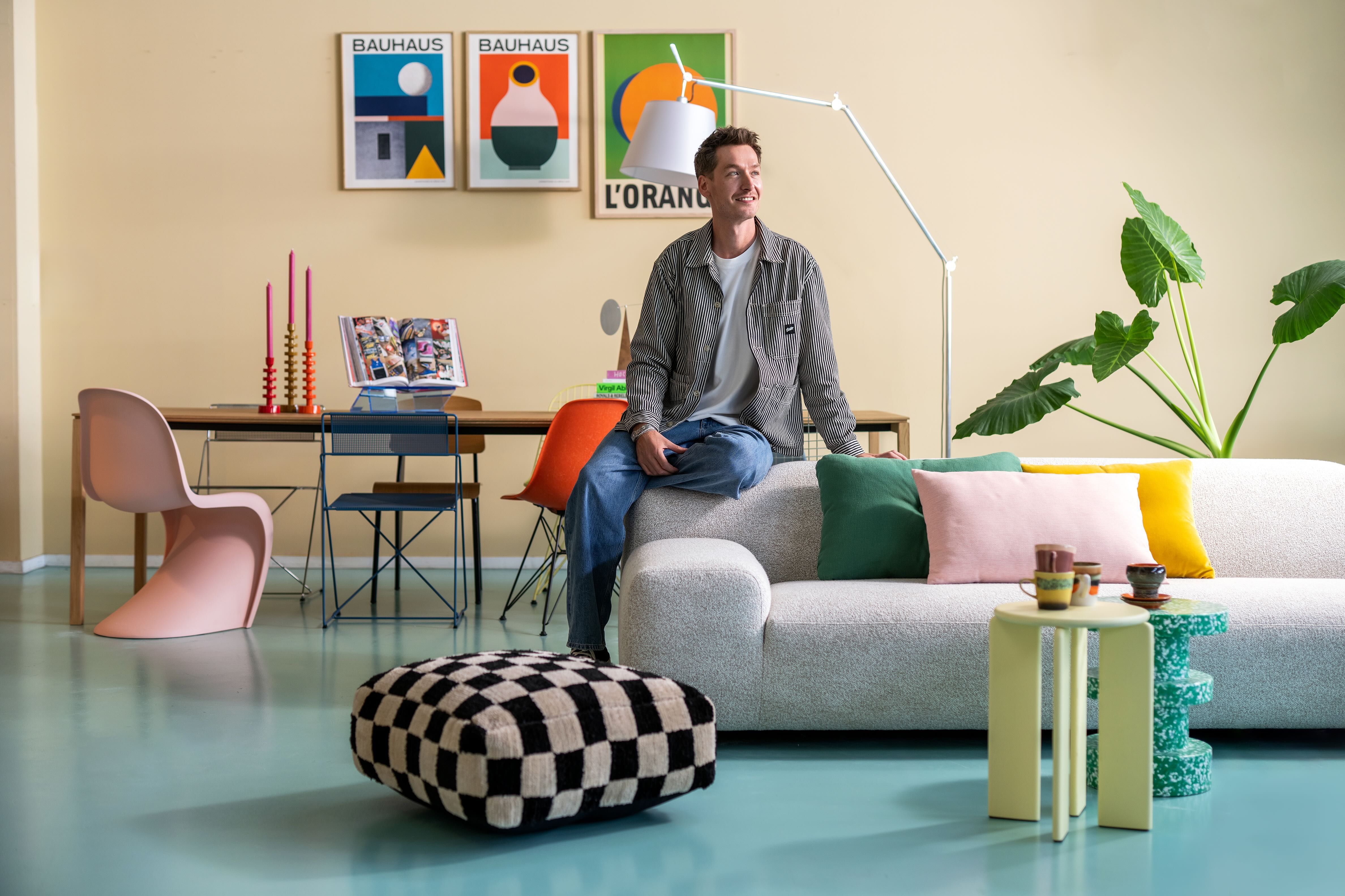 Man zit op grijze bank in woonkamer setting met designer items