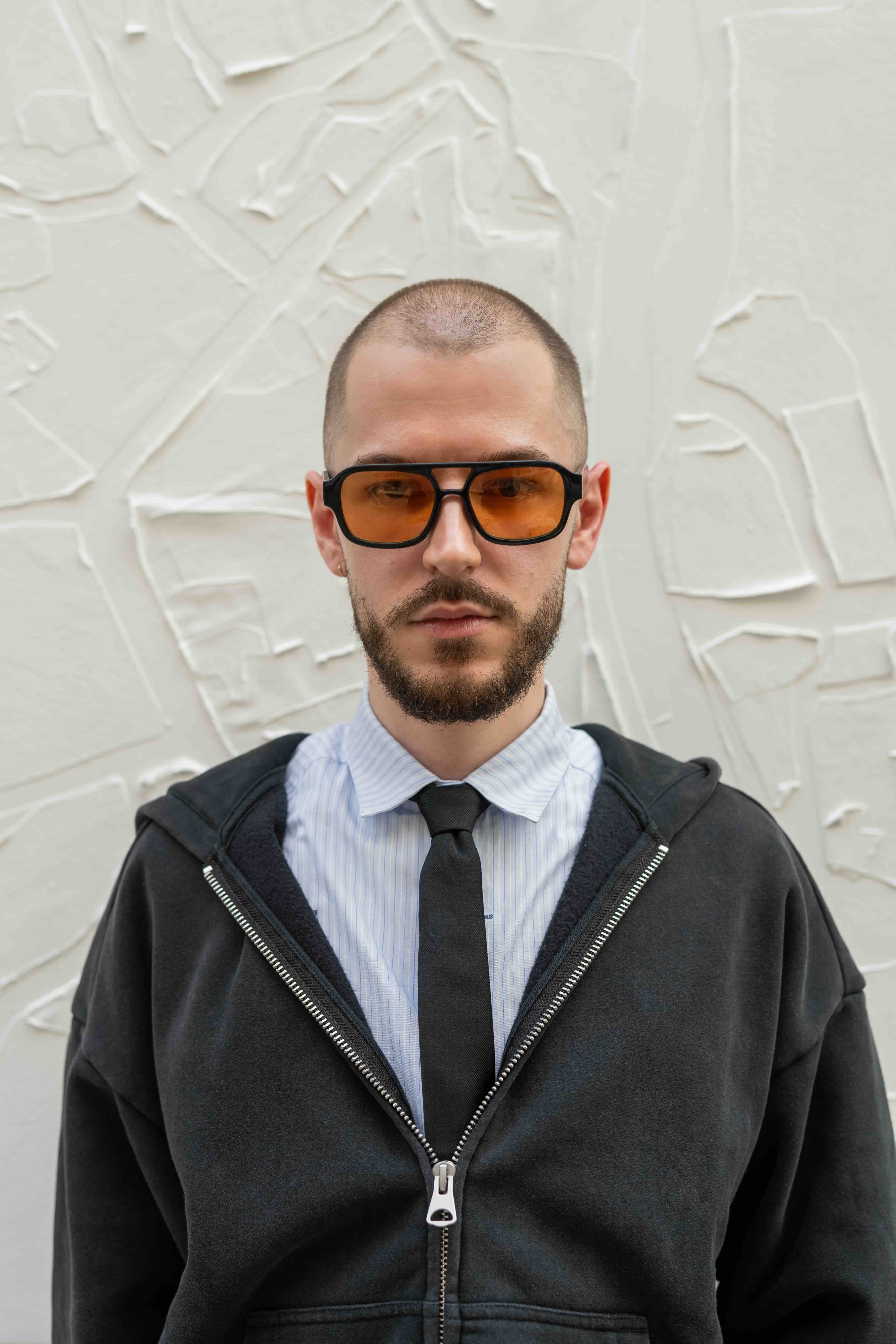 man met oranje zonnebril kijkt in camera