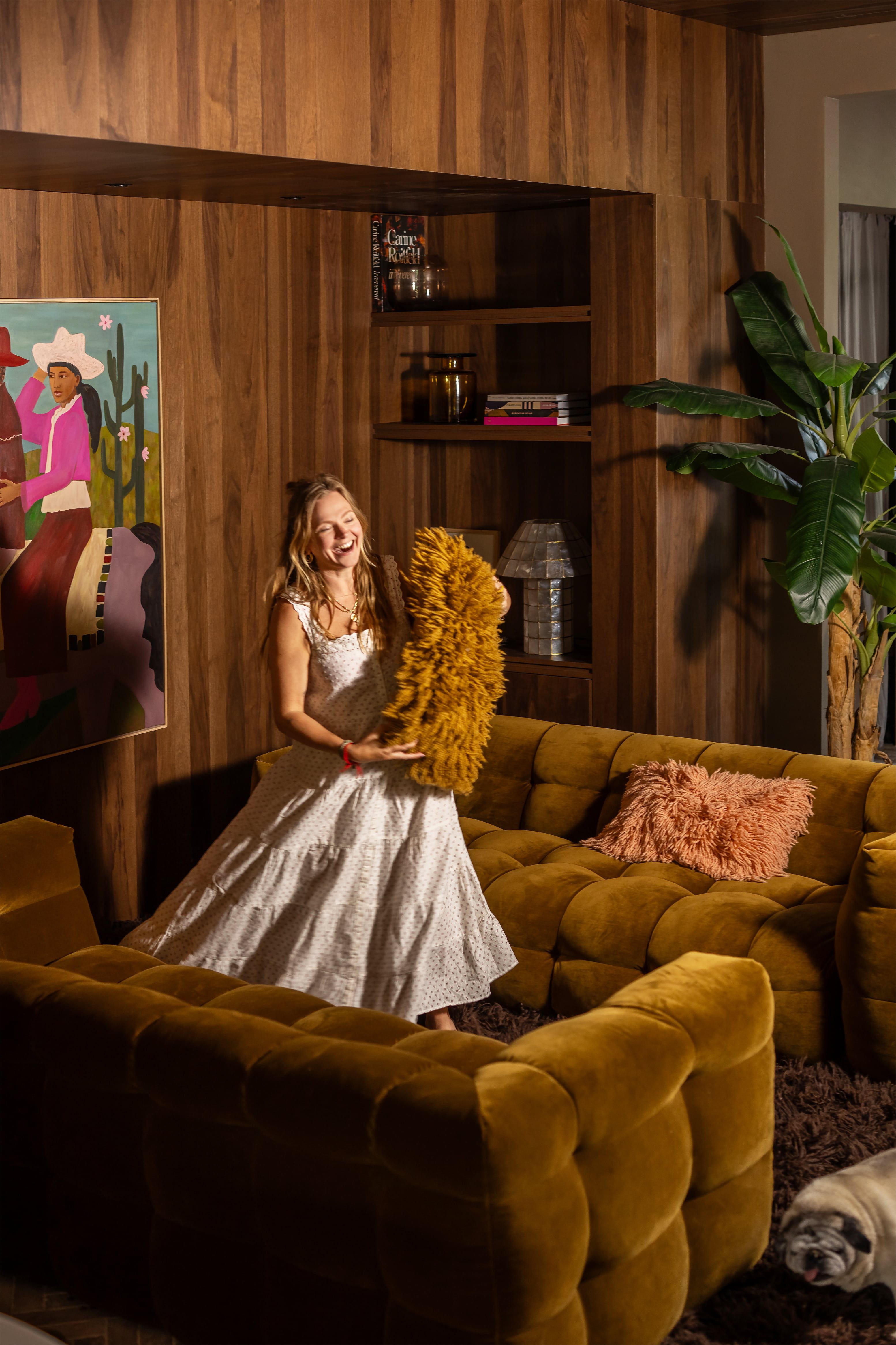 Vrouw in woonkamer met kussen in haar hand