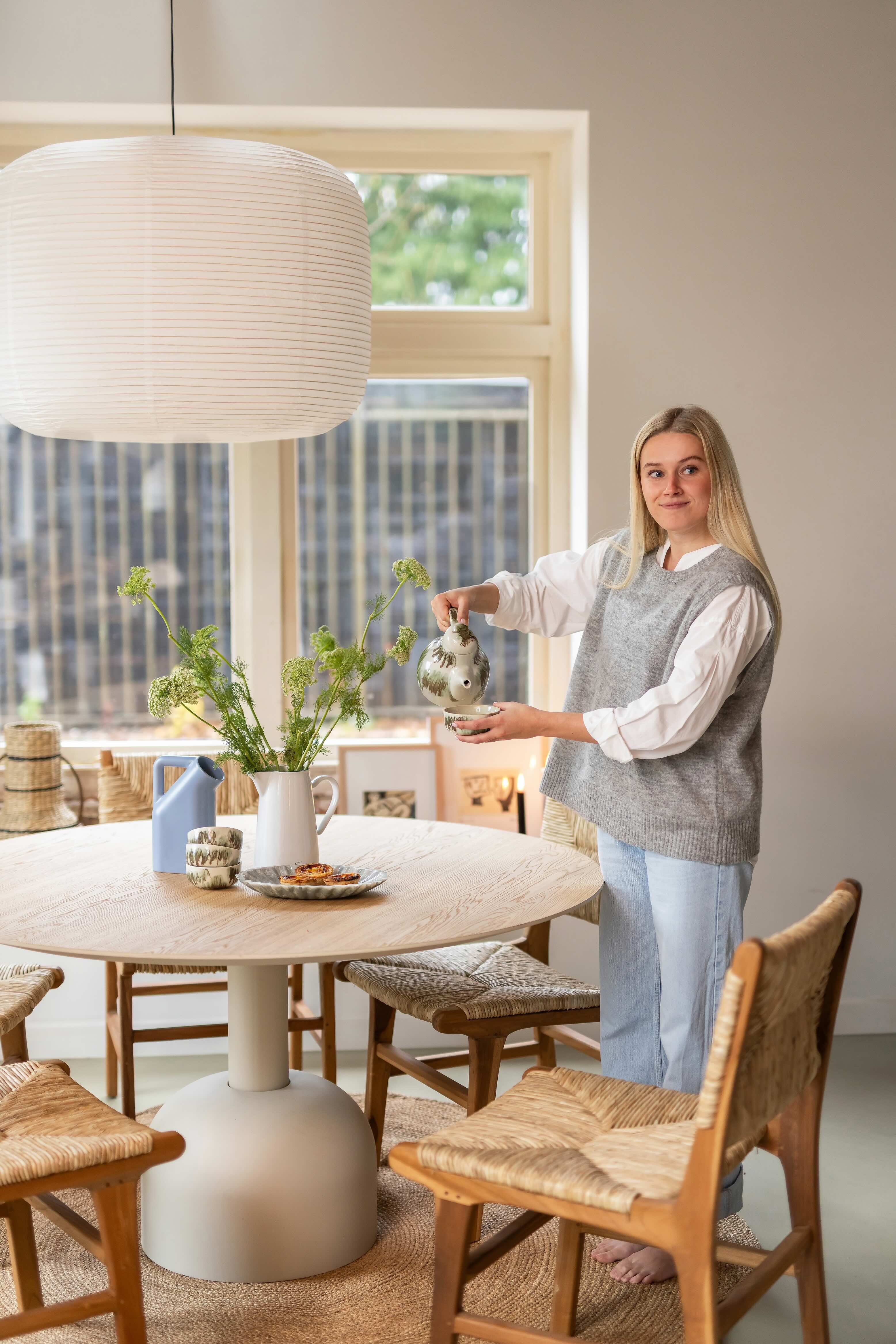 Blonde vrouw staat bij ronde landelijke eettafel