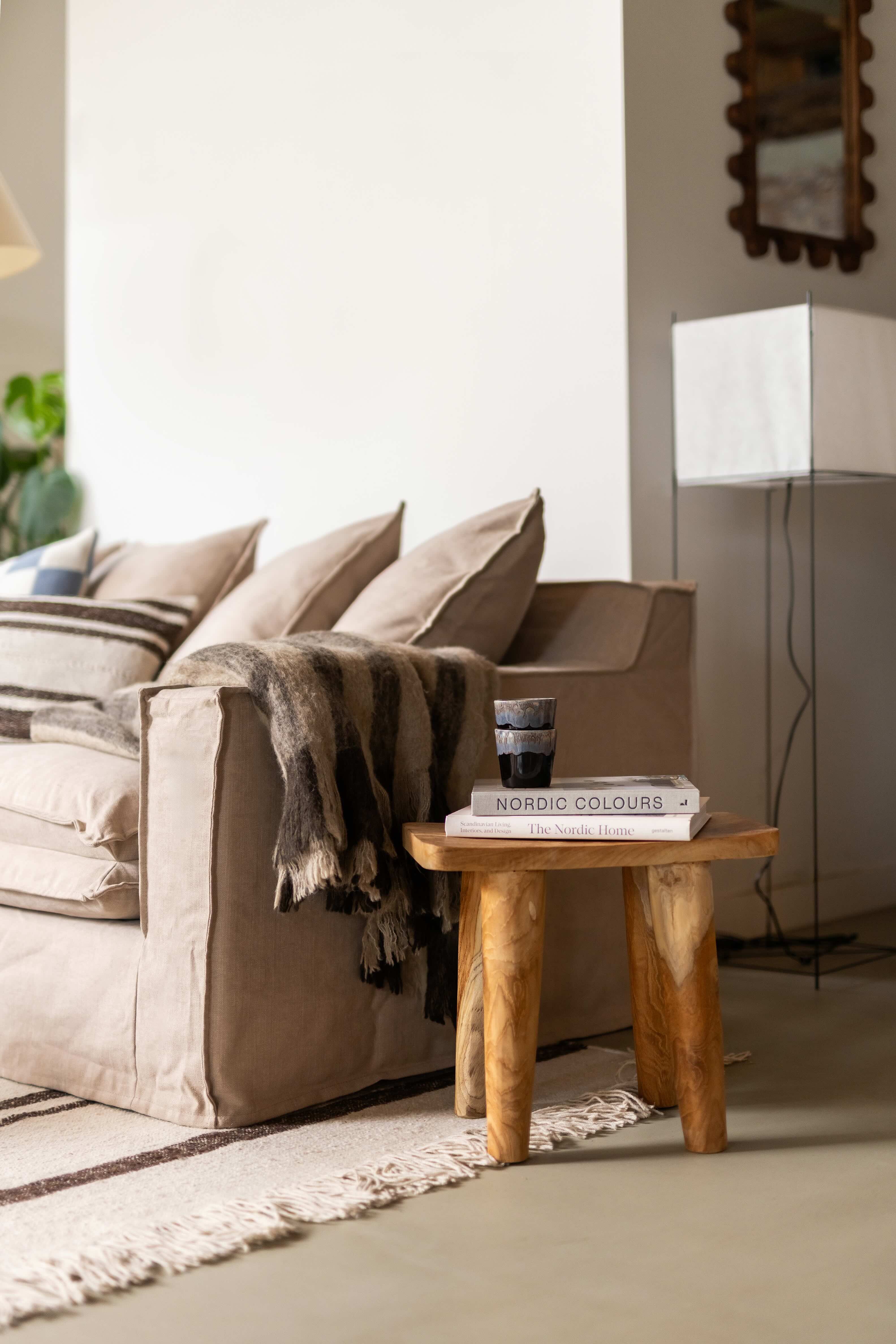 Closeup van beige bank met houten tafeltje met boek erop