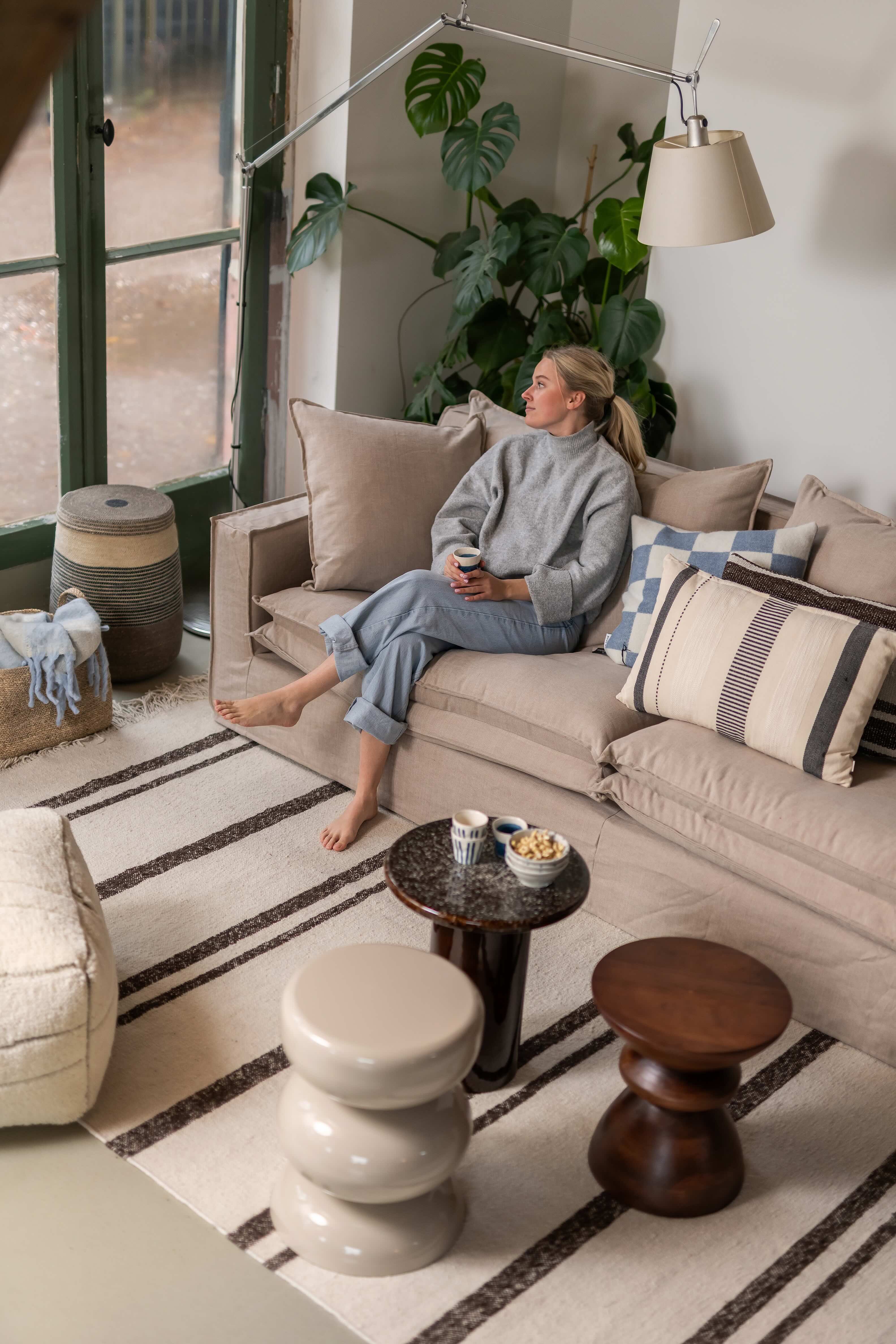 Beige bank in landelijke woonkamer met blonde vrouw op de bank