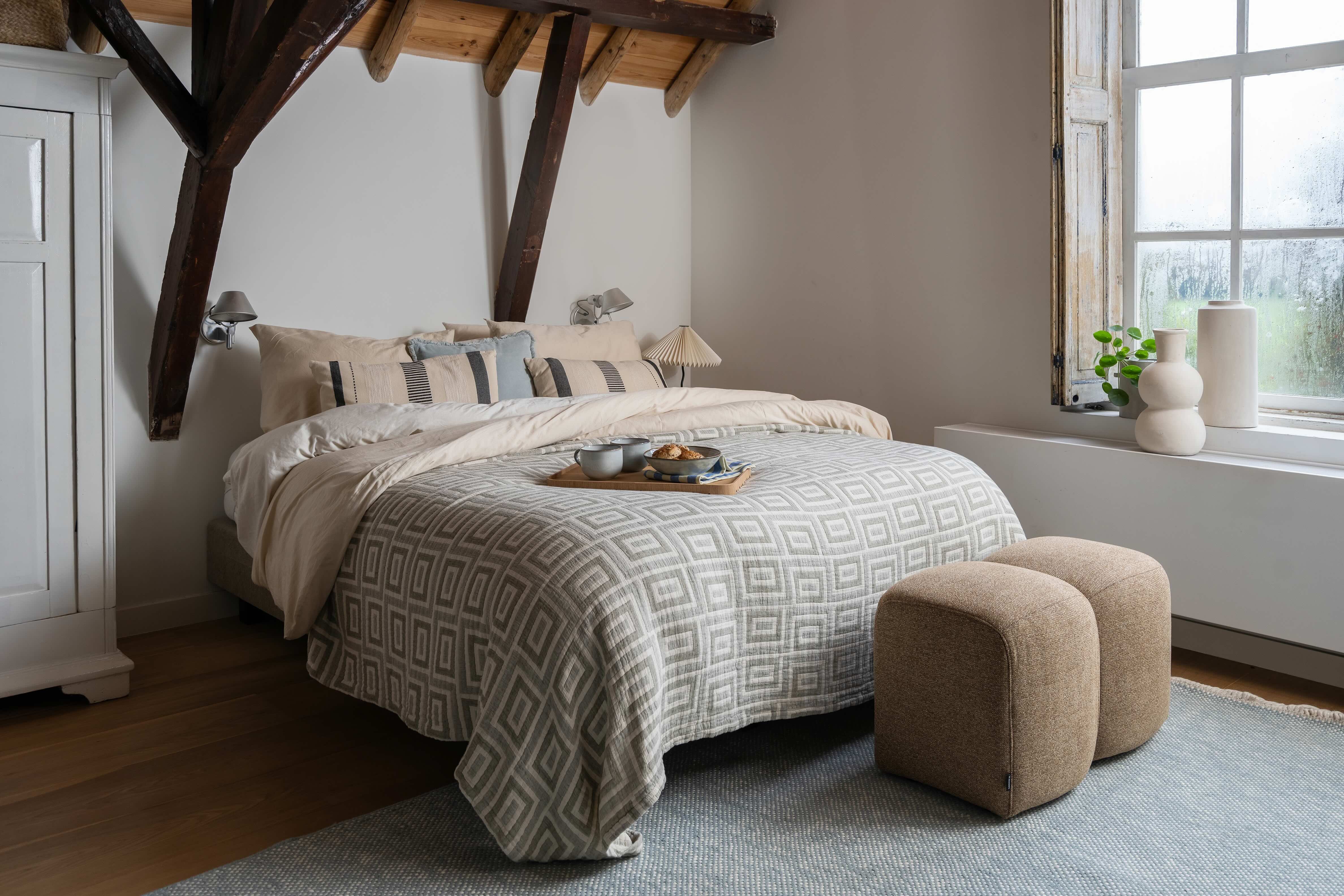 Groot bed in landelijke slaapkamer met veel kussens