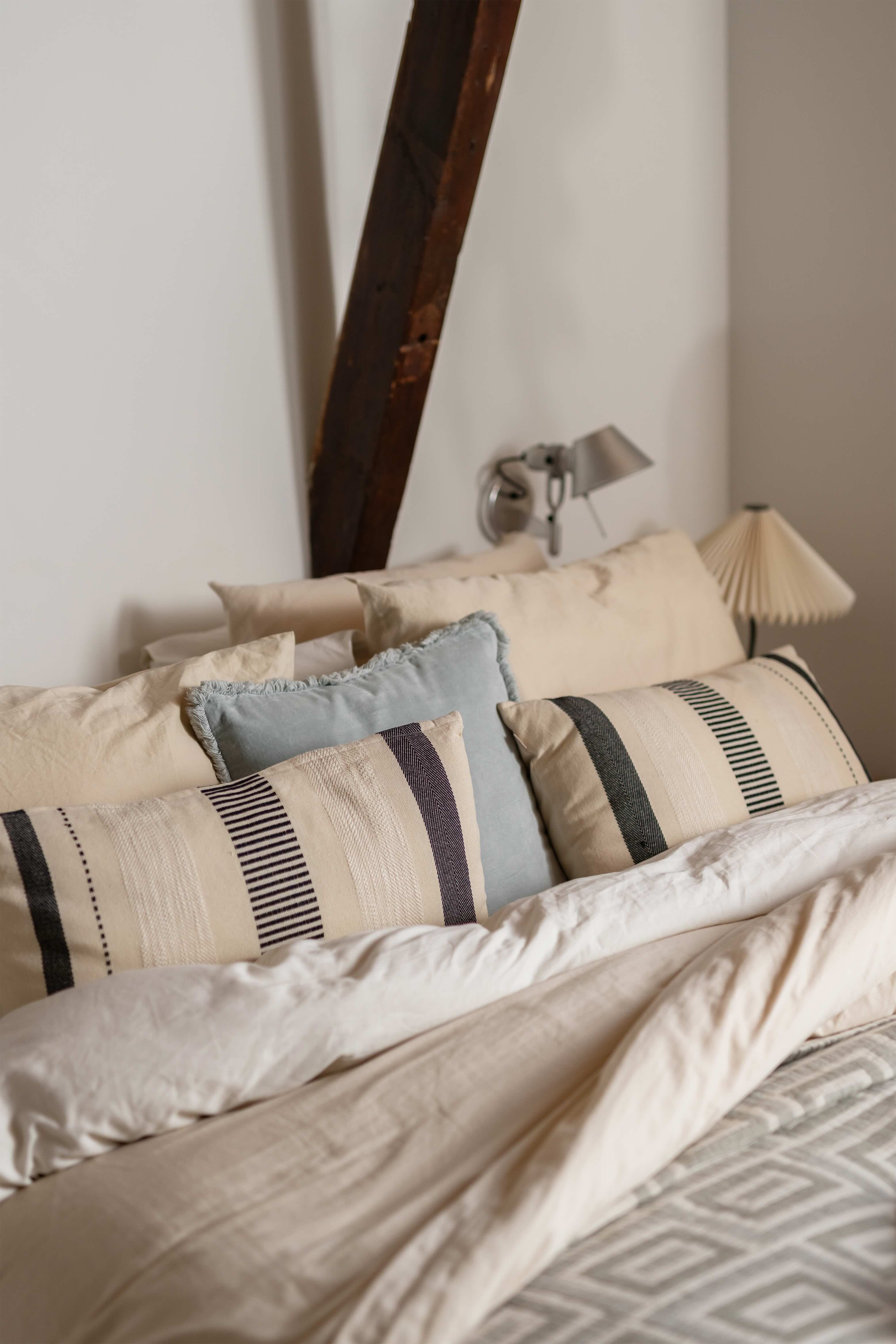 Bed met veel kussens in lichte kleuren