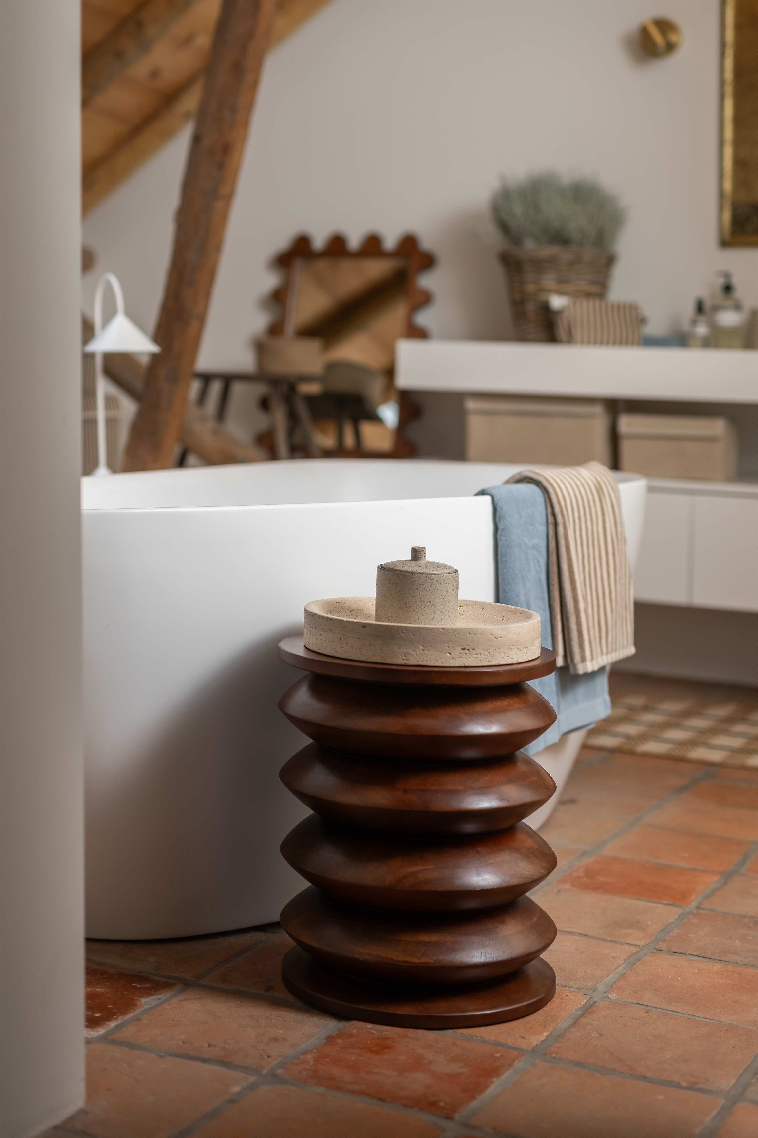 Houten krukje naast wit bad met handdoeken over de rand