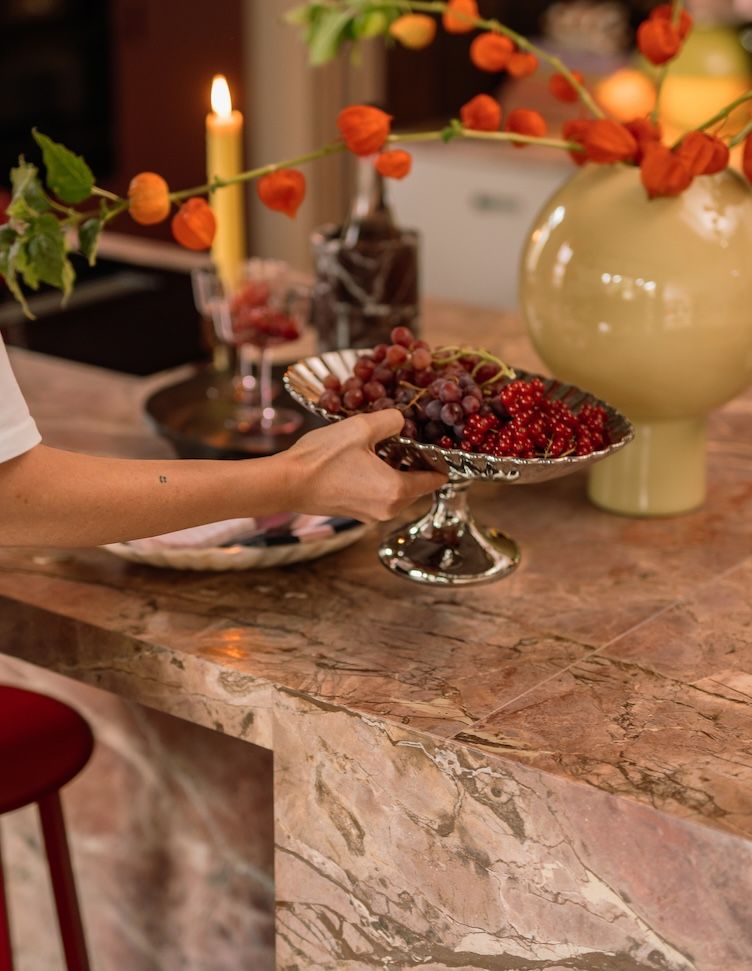 vrouw zet schaal met fruit neer