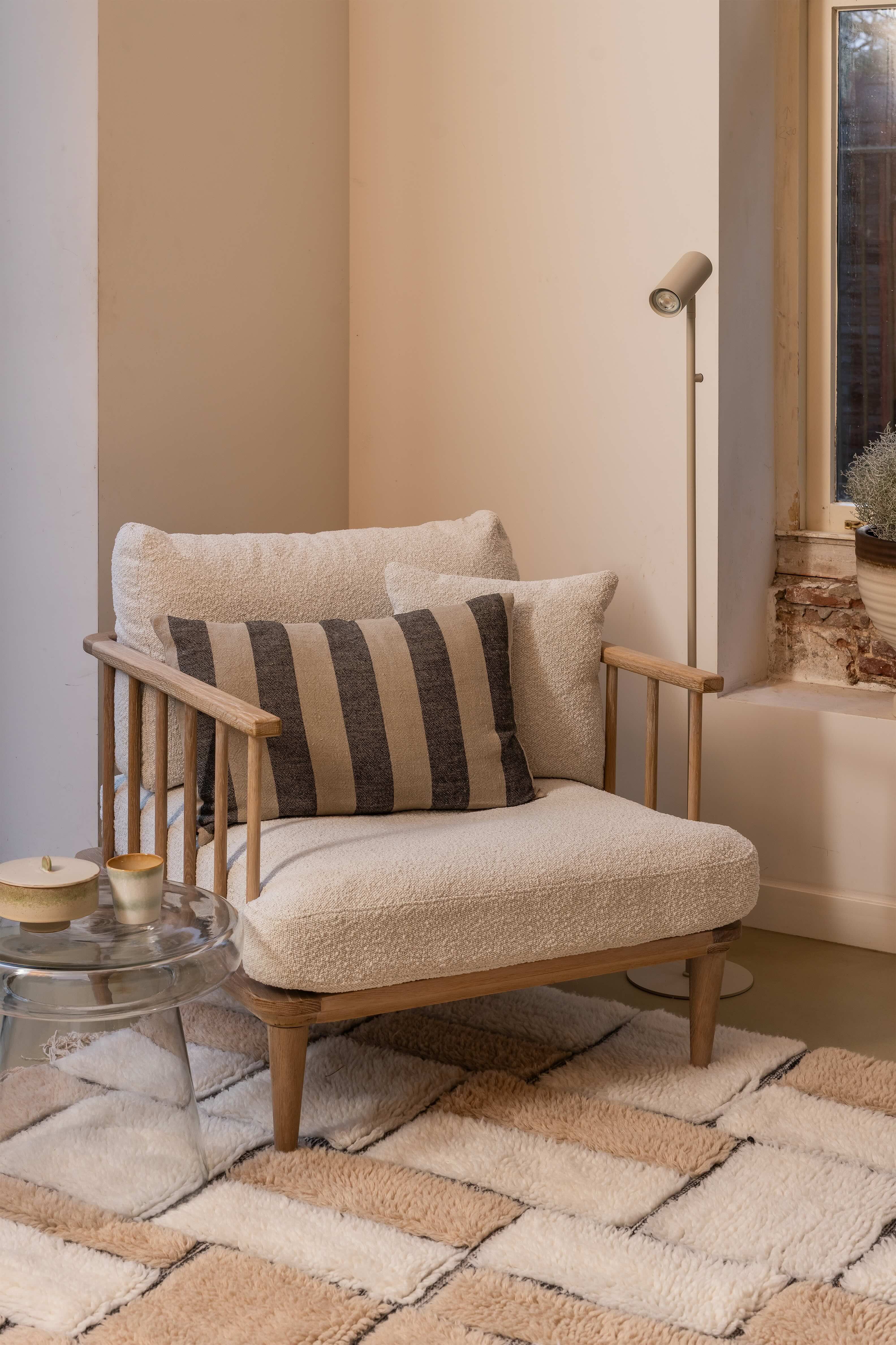 Beige beklede fauteuil met houten frame op geblokt vloerkleed