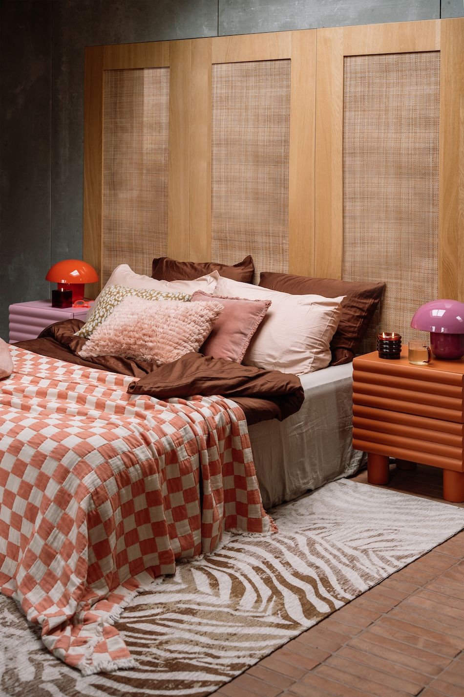 Opgemaakt bed met veel kussens en nachtkastje