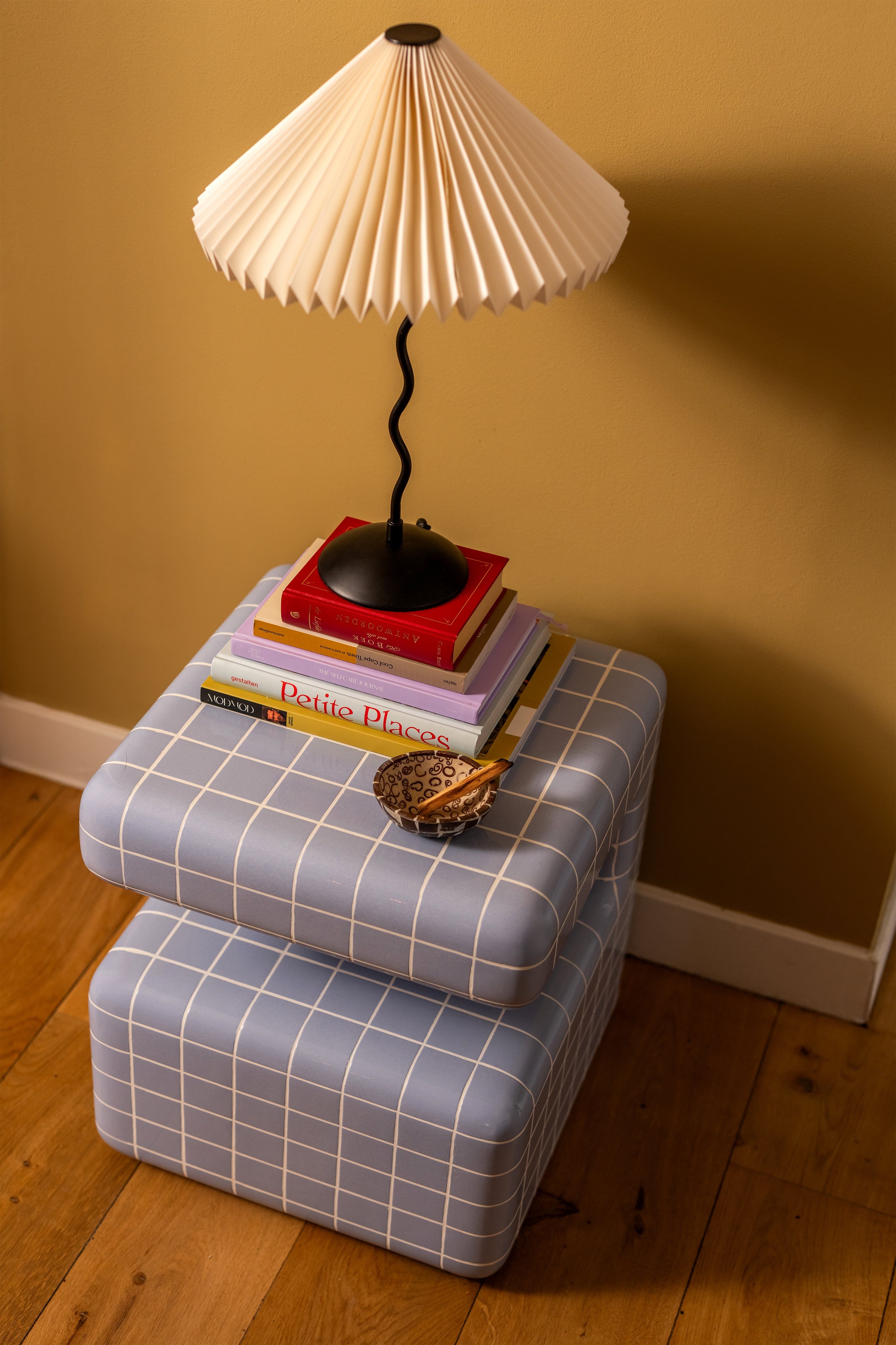 Blauwe bijzettafel met tafellamp op een stapel boeken