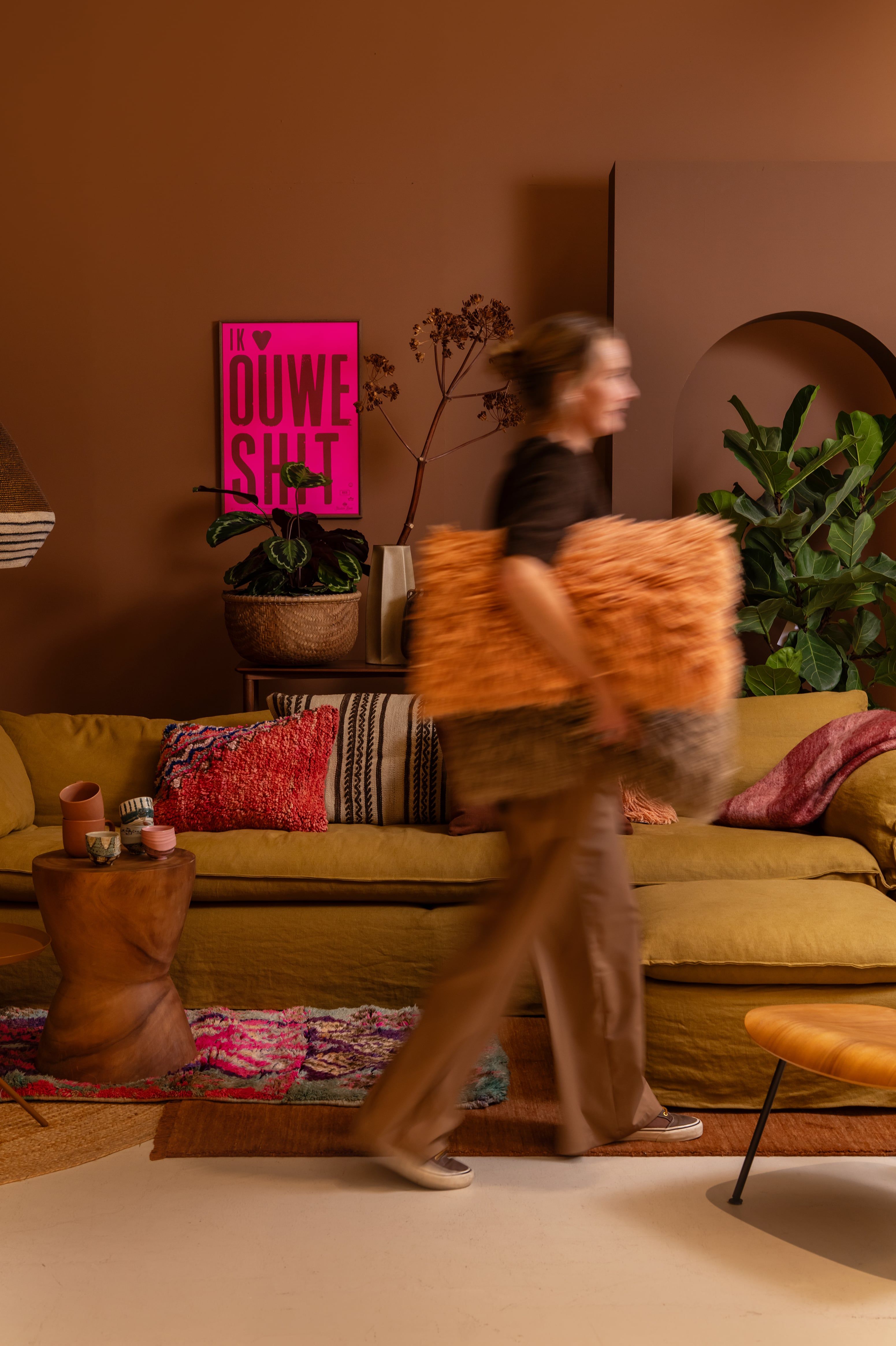 vrouw loopt door woonkamer met kussen onder haar arm