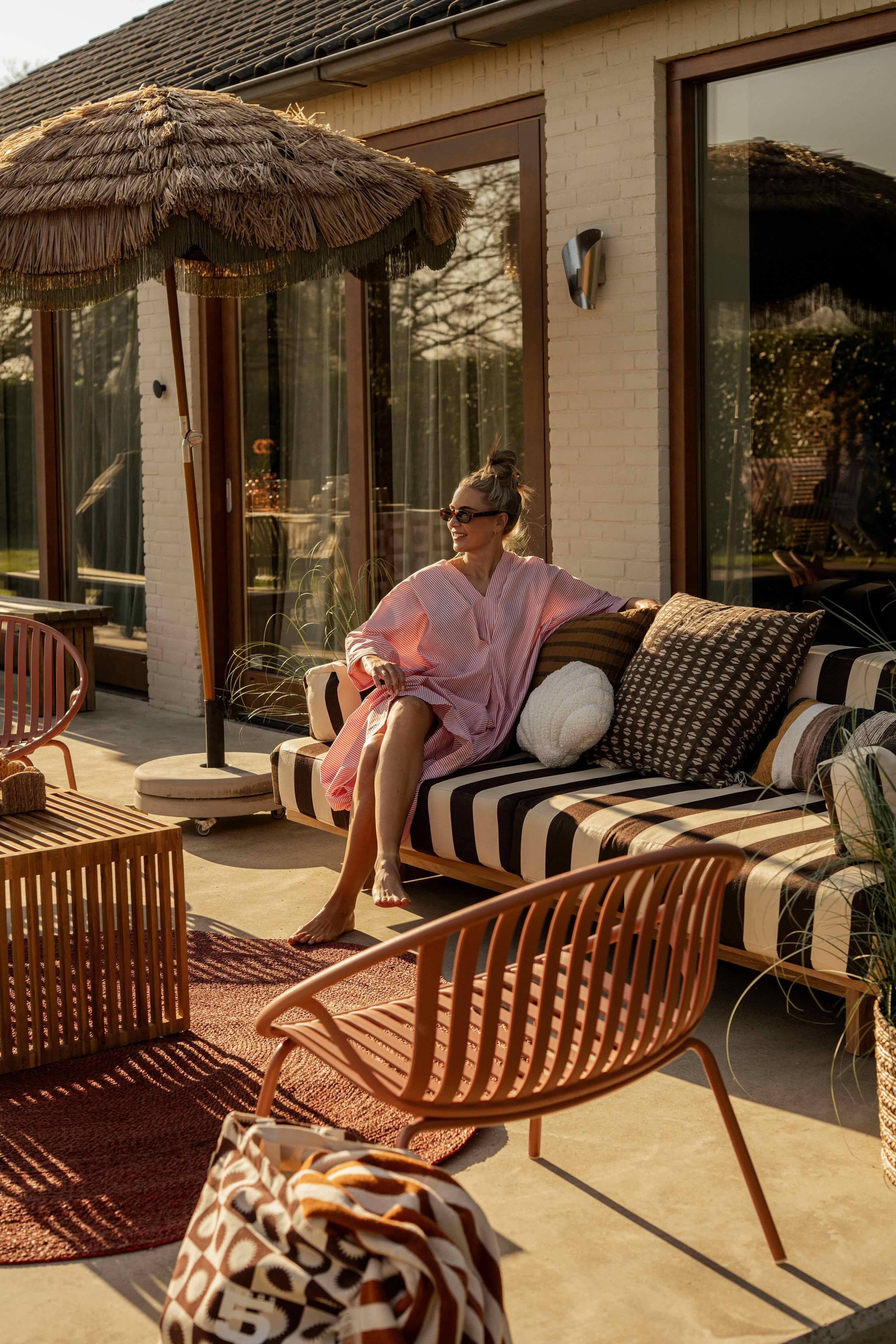 Vrouw op gestreepte loungebank onder parasol