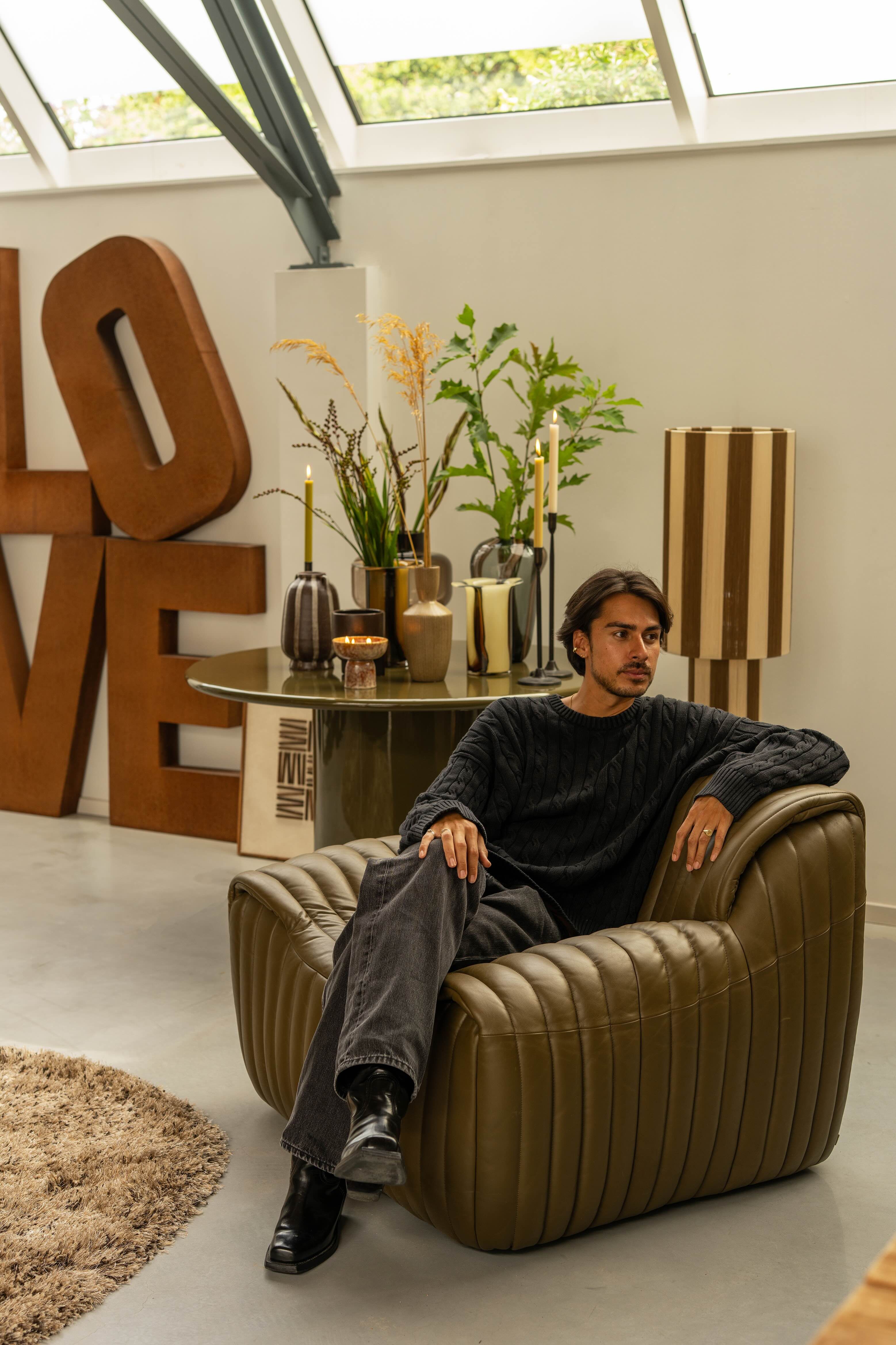 Man zit in grote leren fauteuil