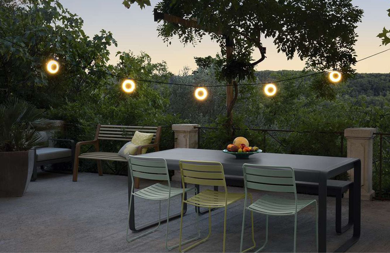 Lichtslinger bolletjes boven tuintafel met zonsondergang
