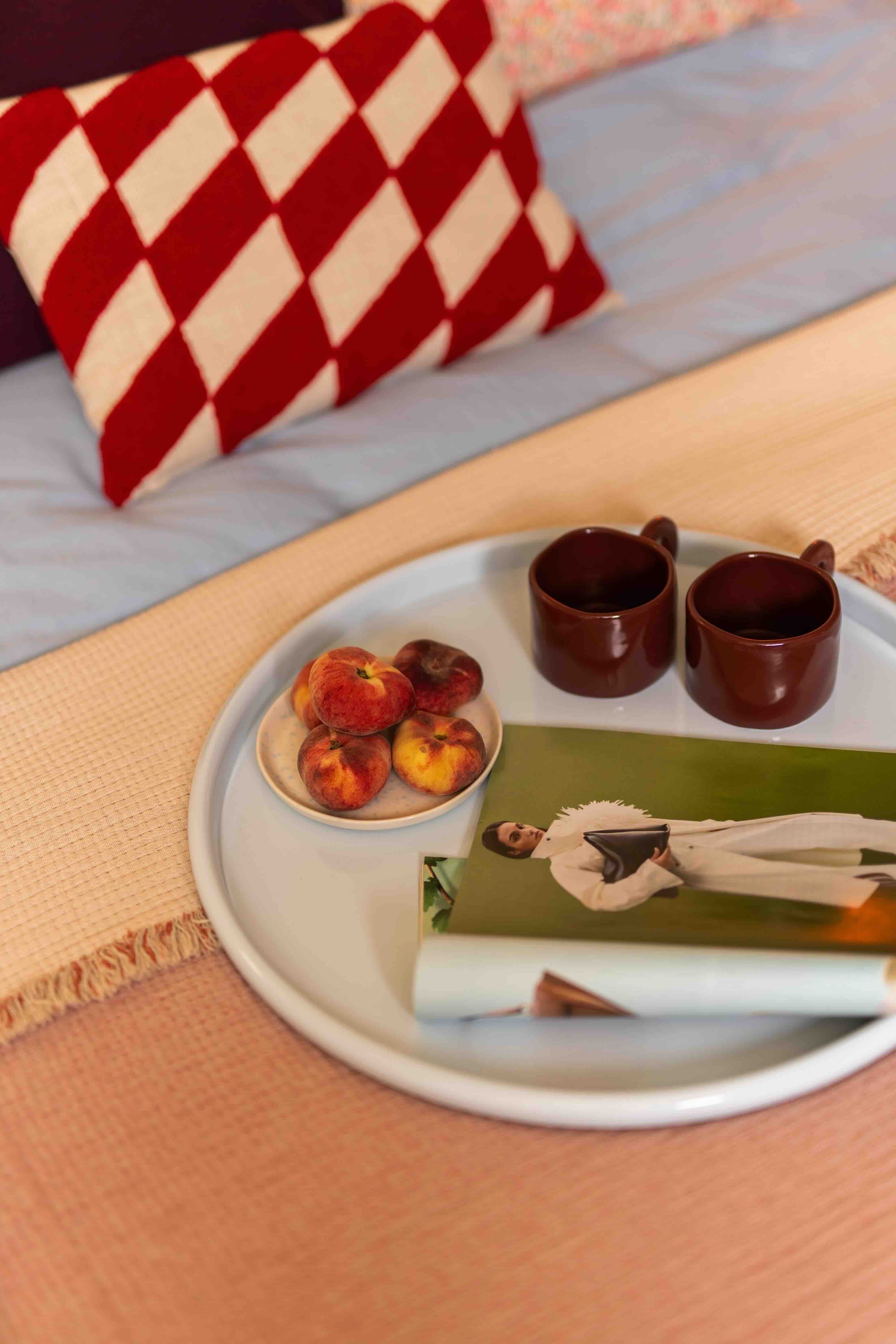 dienblad op bed met fruit en kopjes thee
