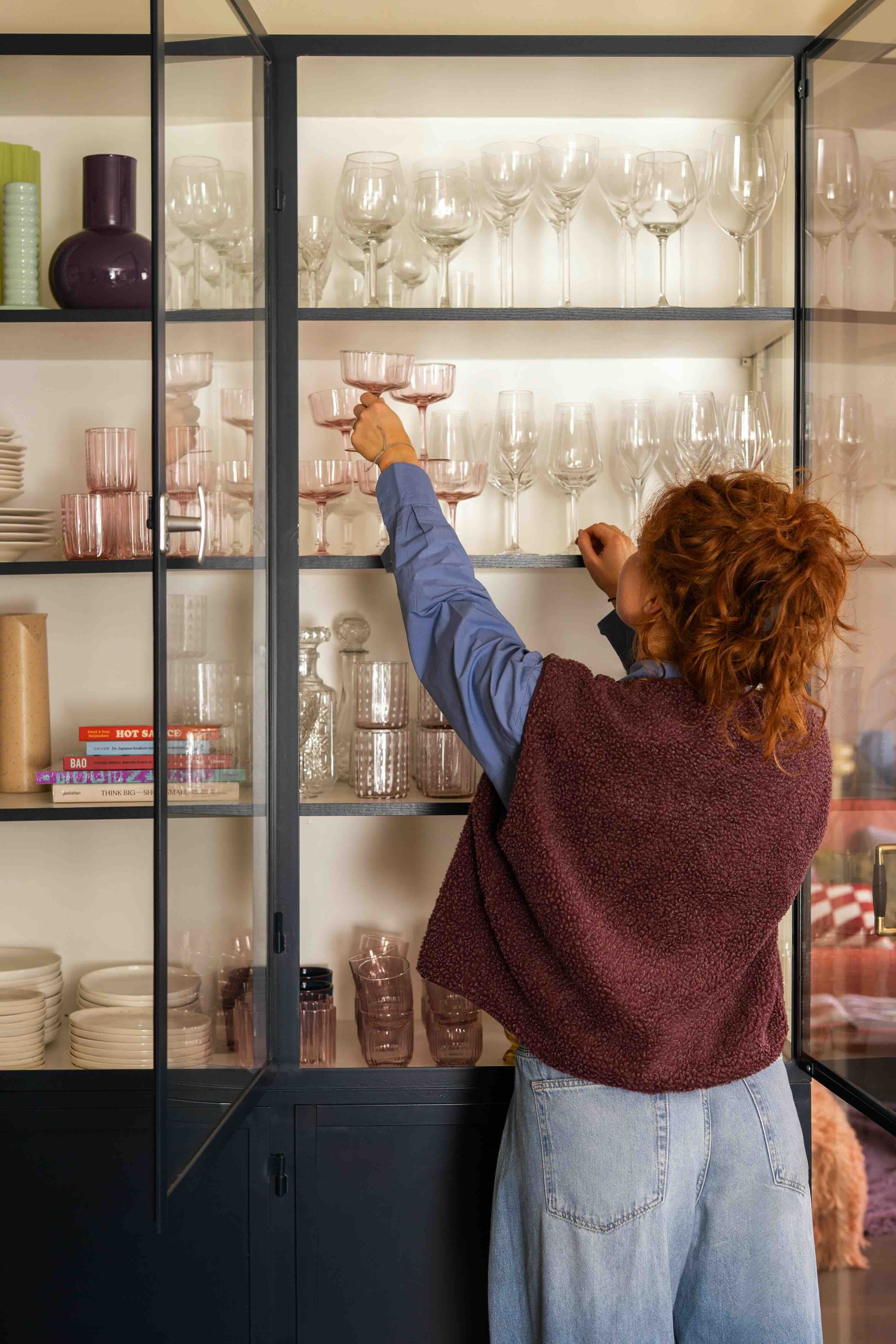 vrouw zet glas in servieskast