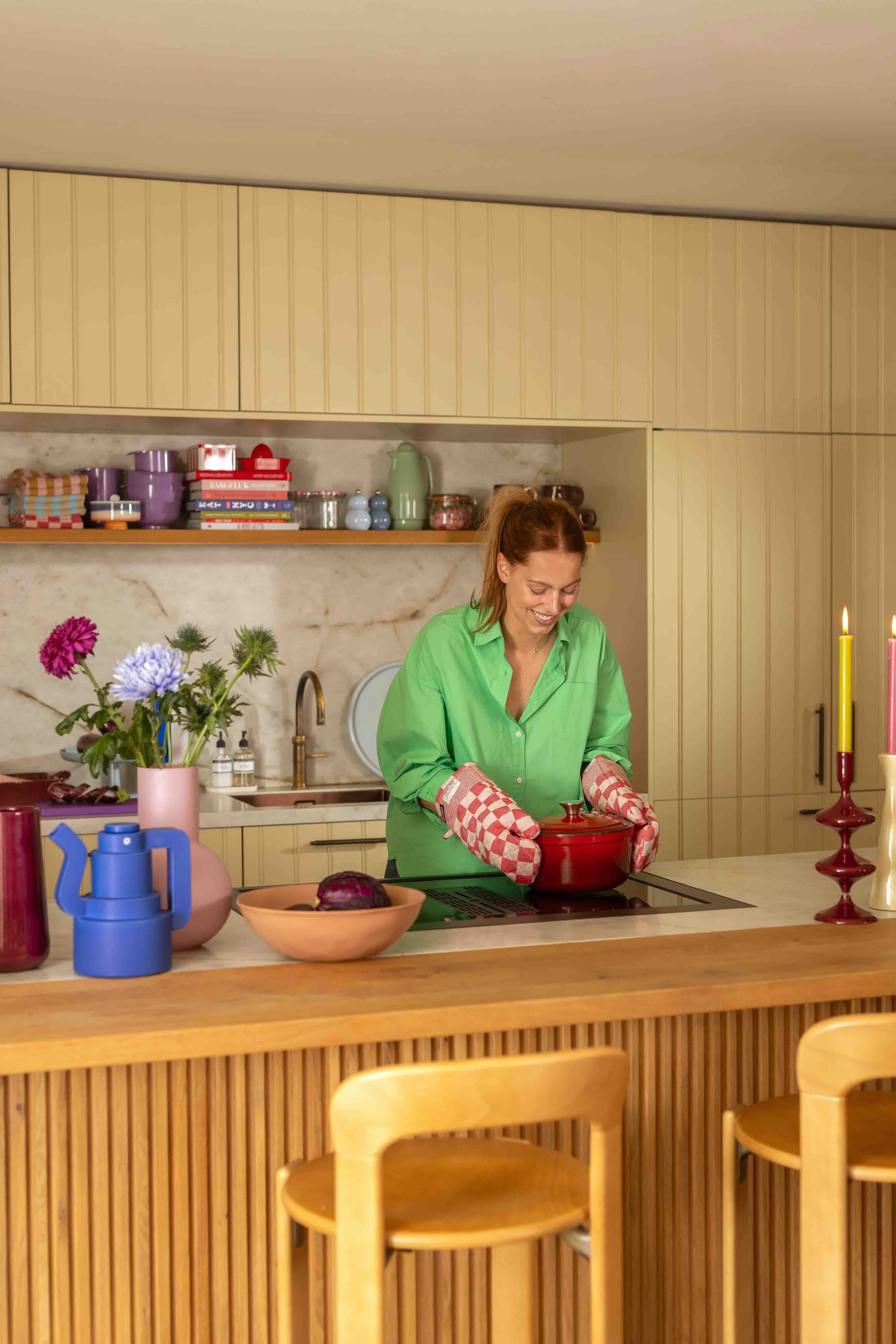 vrouw staat in keuken met pan in handen