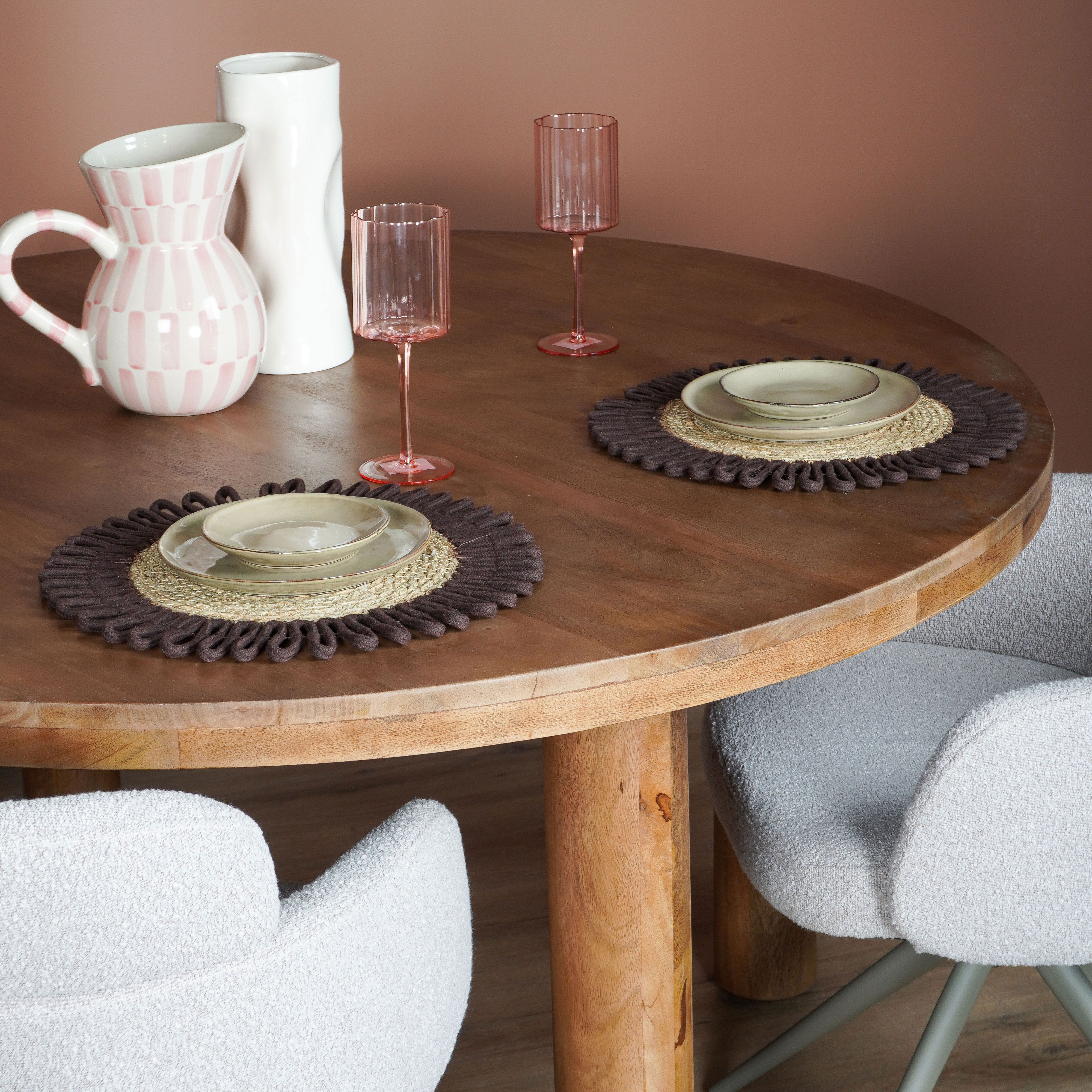 Houten ronde eettafel met servies en lichte stoelen