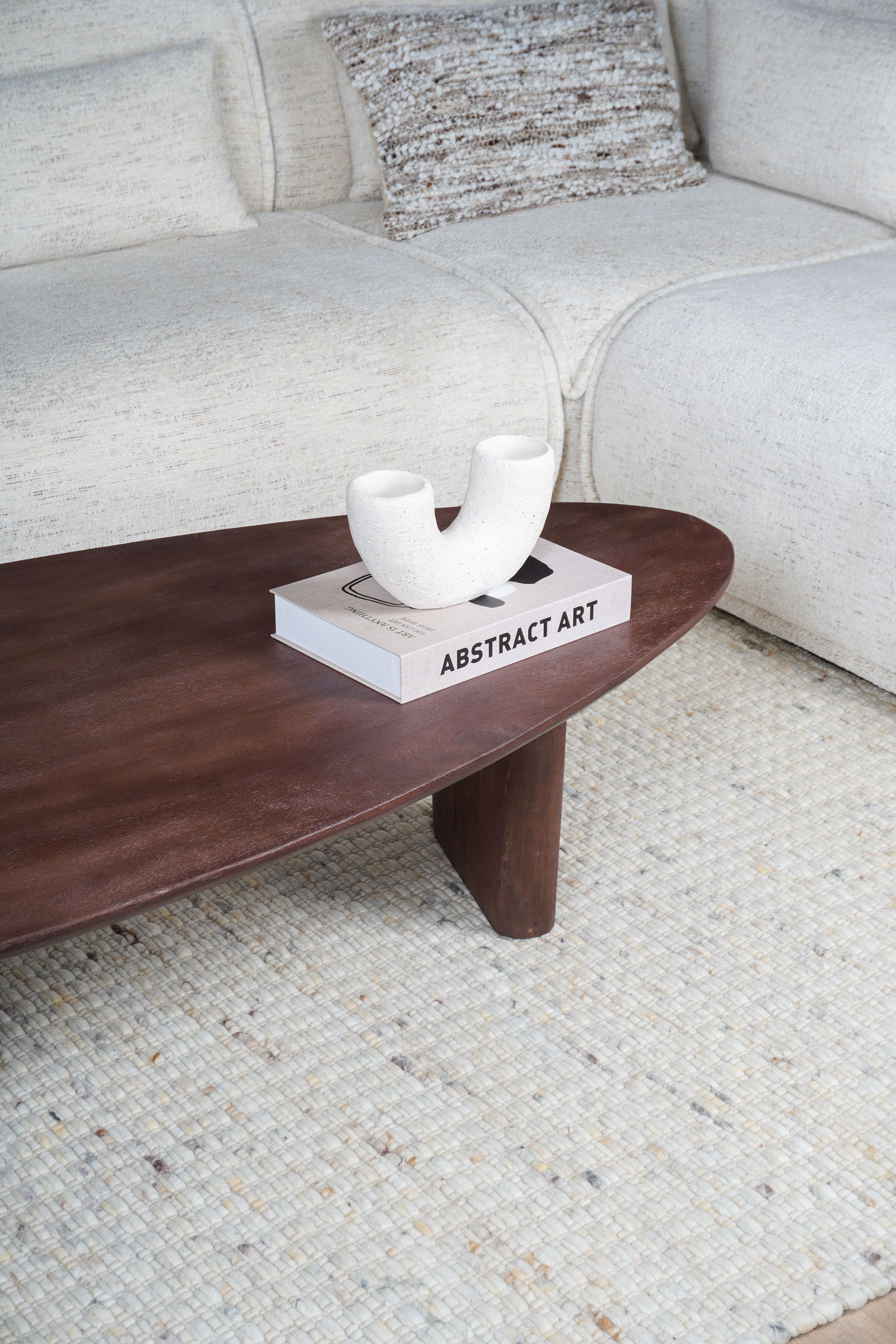 Donker houten salontafel op licht kleed met lichte bank