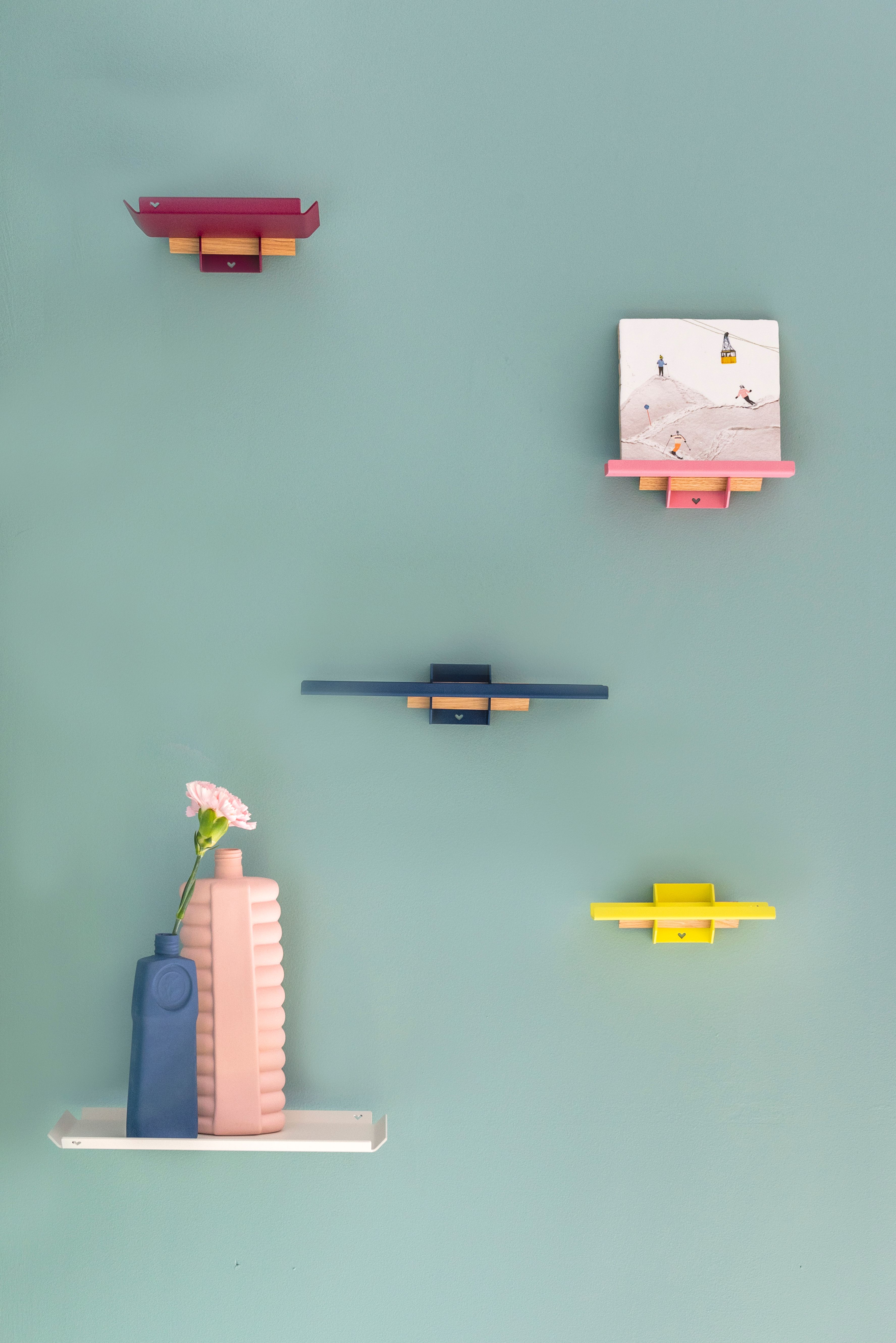 Gekleurde metalen wandplankjes met decoratie op lichtblauwe muur