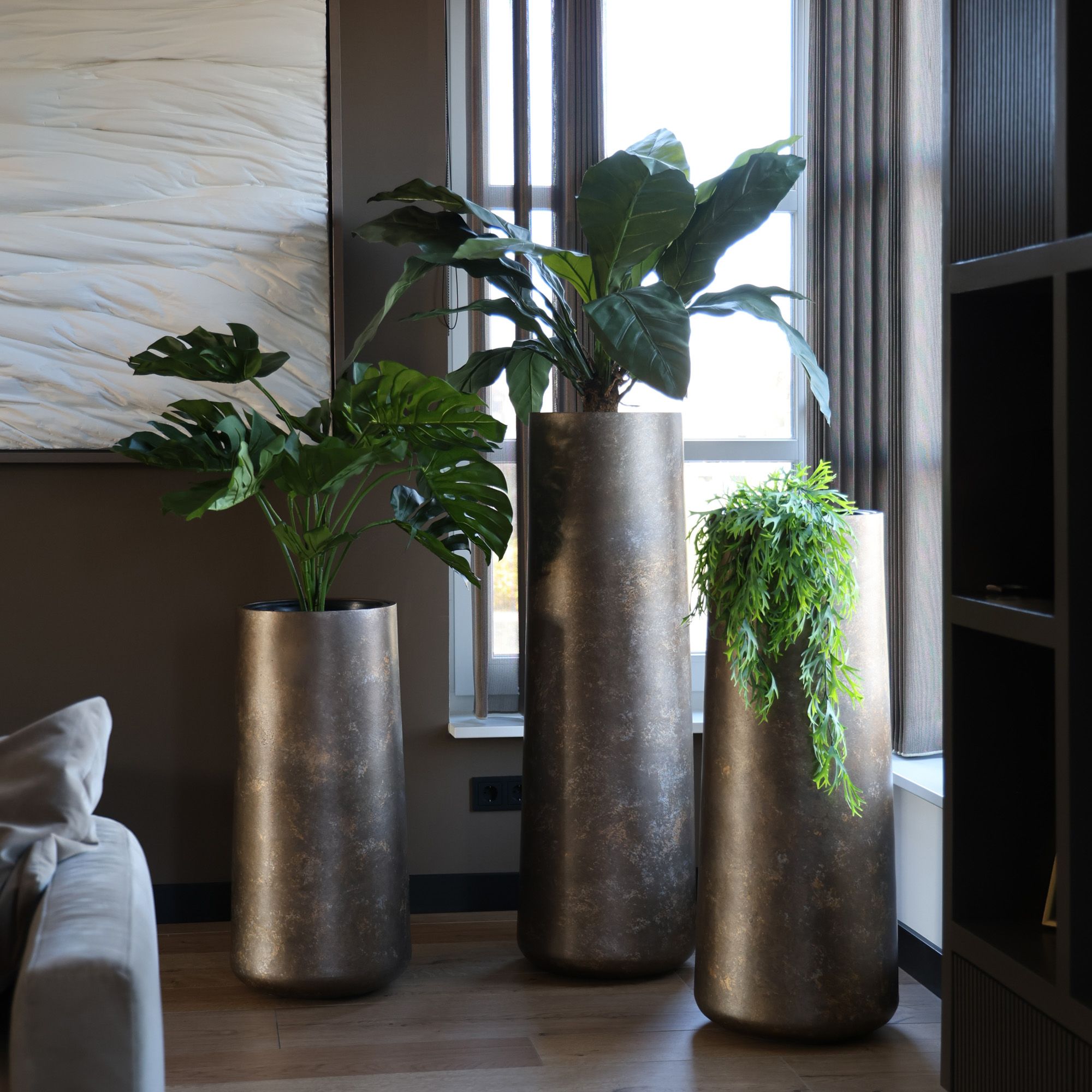 3 hoge metalen bloempotten met planten erin
