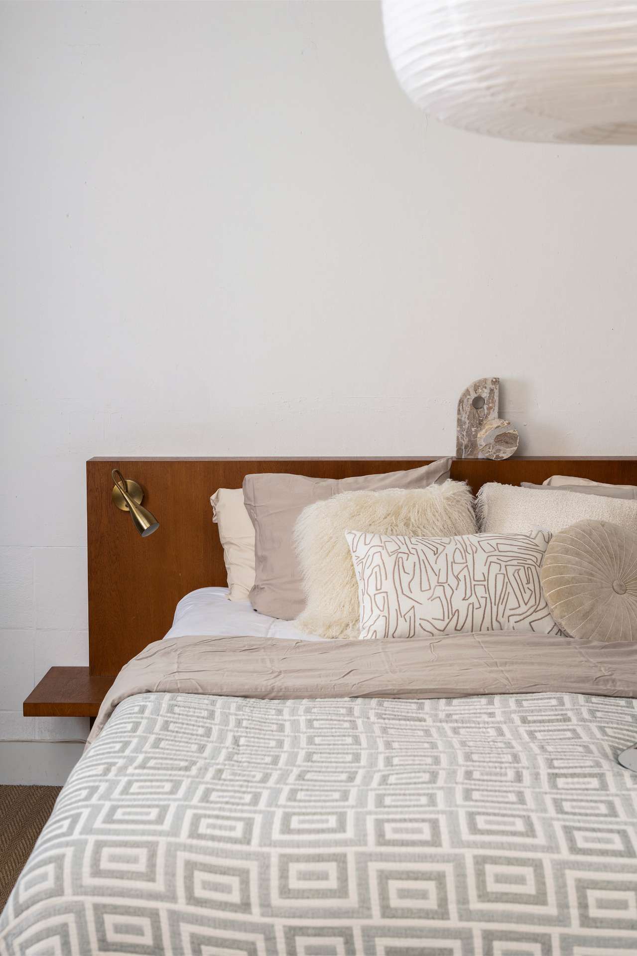 Beige opgemaakt bed met kussens en sprei met print