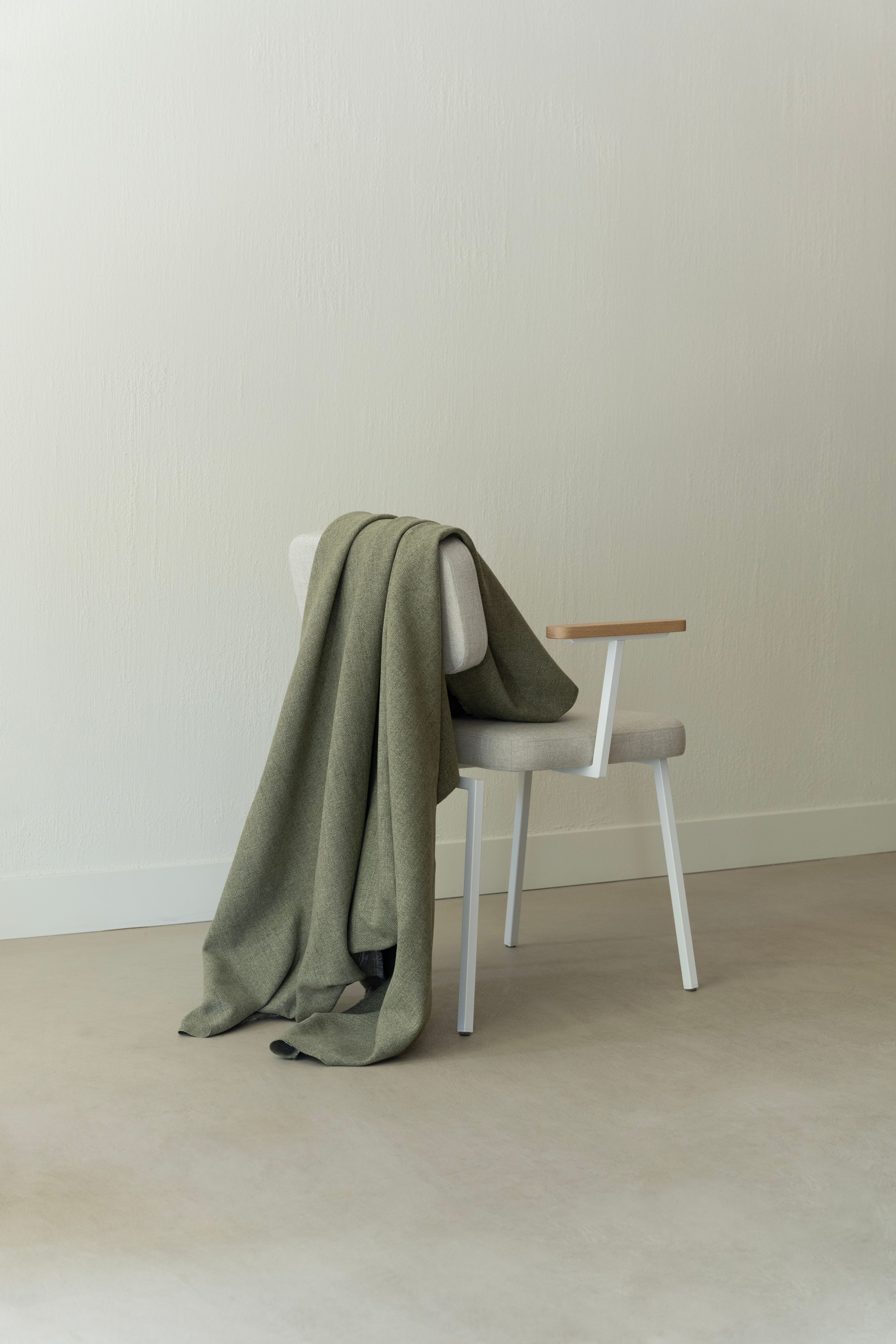 Beklede stoel met wit metalen frame met een plaid over de rugleuning heen