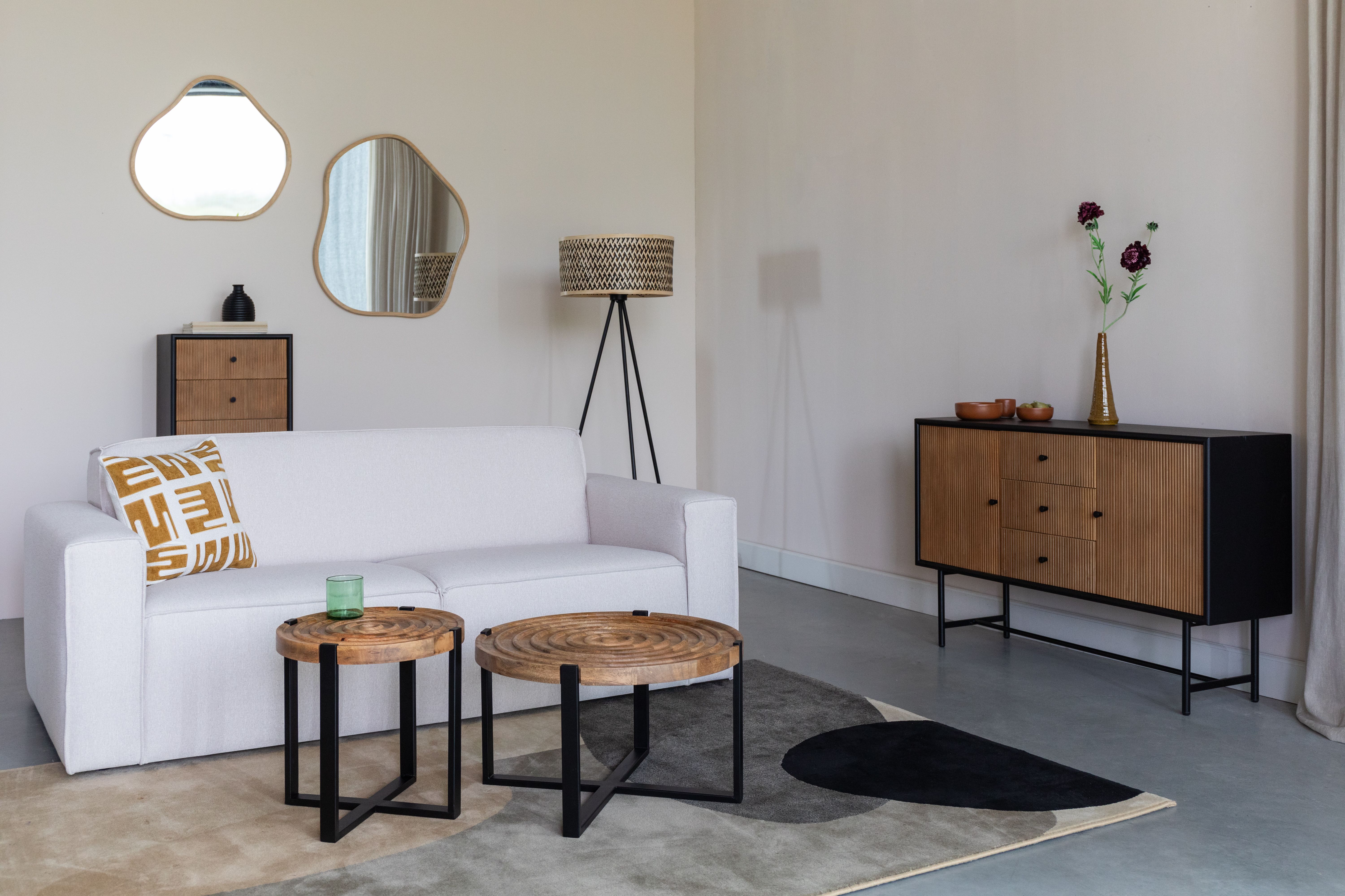 Woonkamer met witte bank en houten salontafels en dressoir