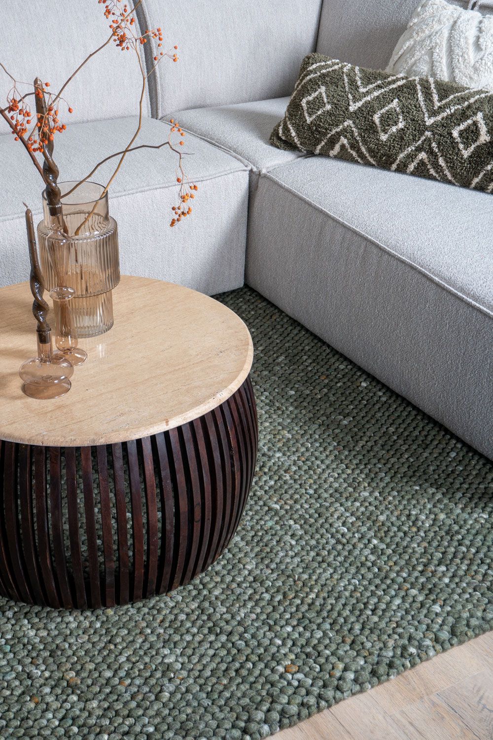 Lichtgrijze bank met ronde salontafel en groen vloerkleed