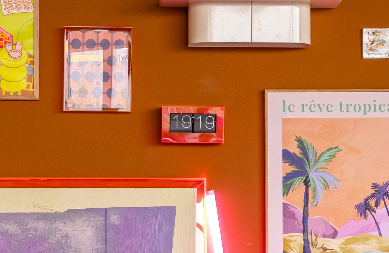 Neon roze wekker aan muur tussen kunst