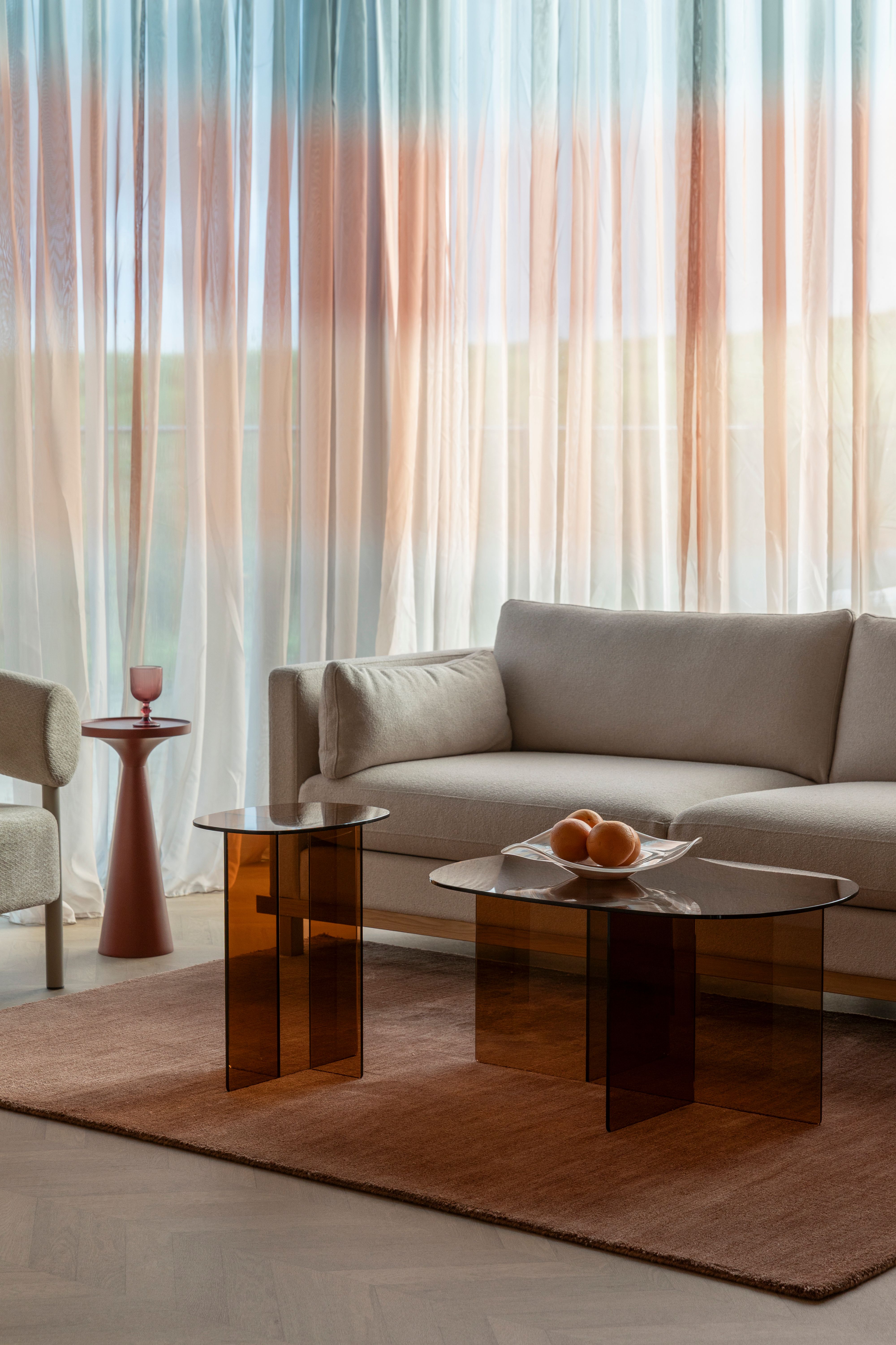 Beige bank met 2 bruin glazen salontafels en kleed