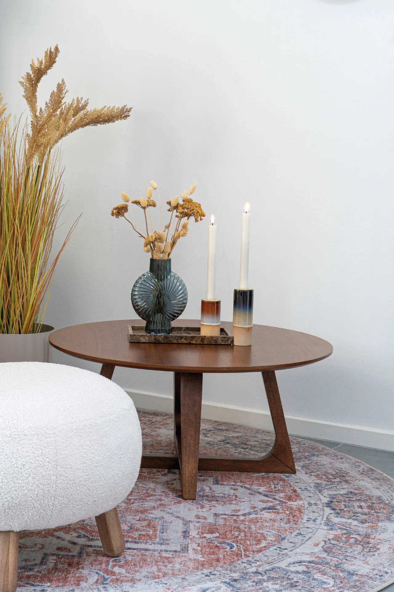 Houten bijzettafel op vloerkleed met accessoires en planten