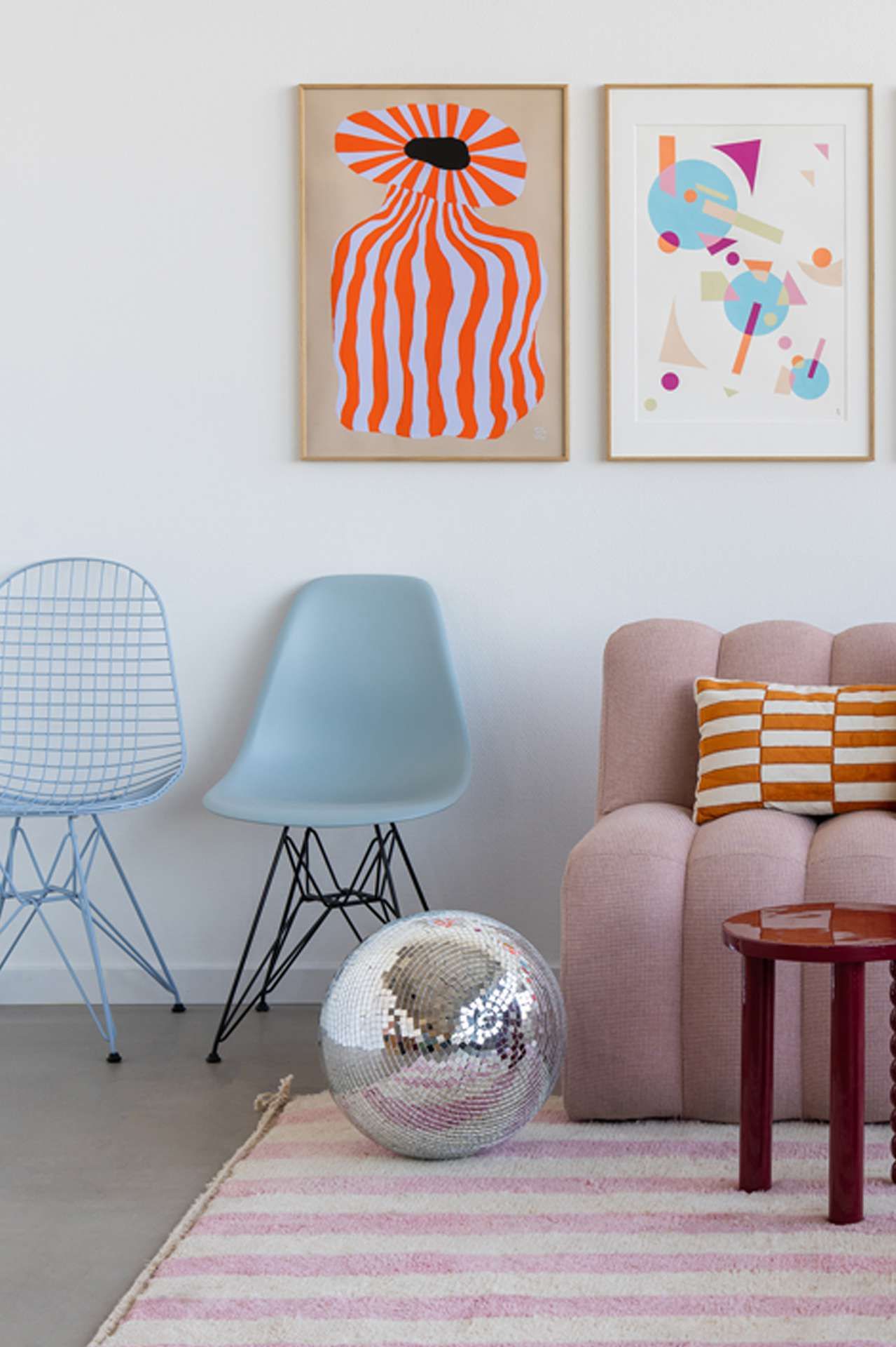 Artwall met roze candy bankje en lichtblauwe vitra stoelen