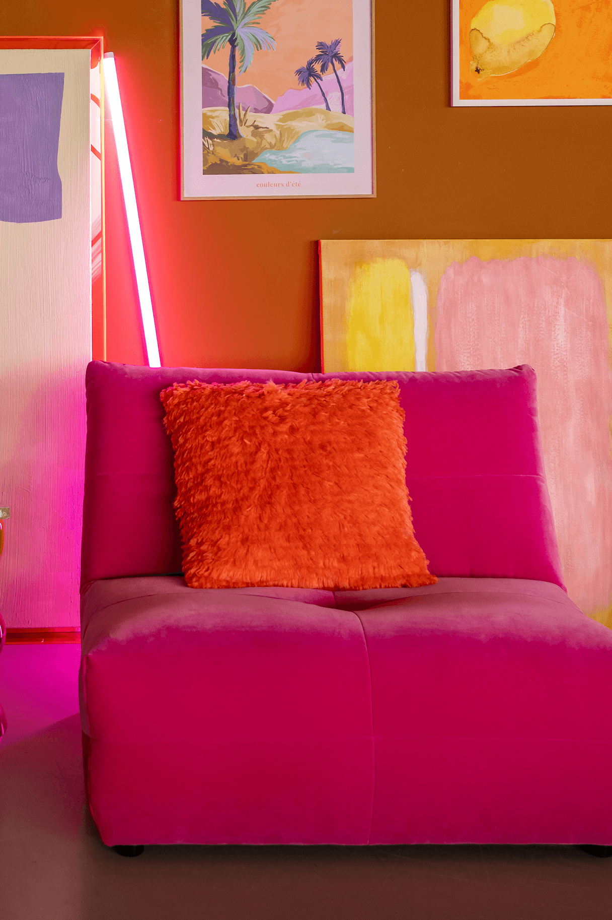 grote roze fauteuil met oranje sierkussen