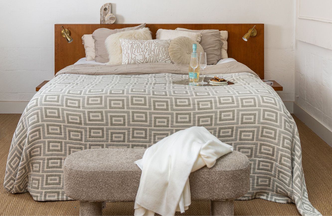 Beige kleurig bed met sprei met een patroon