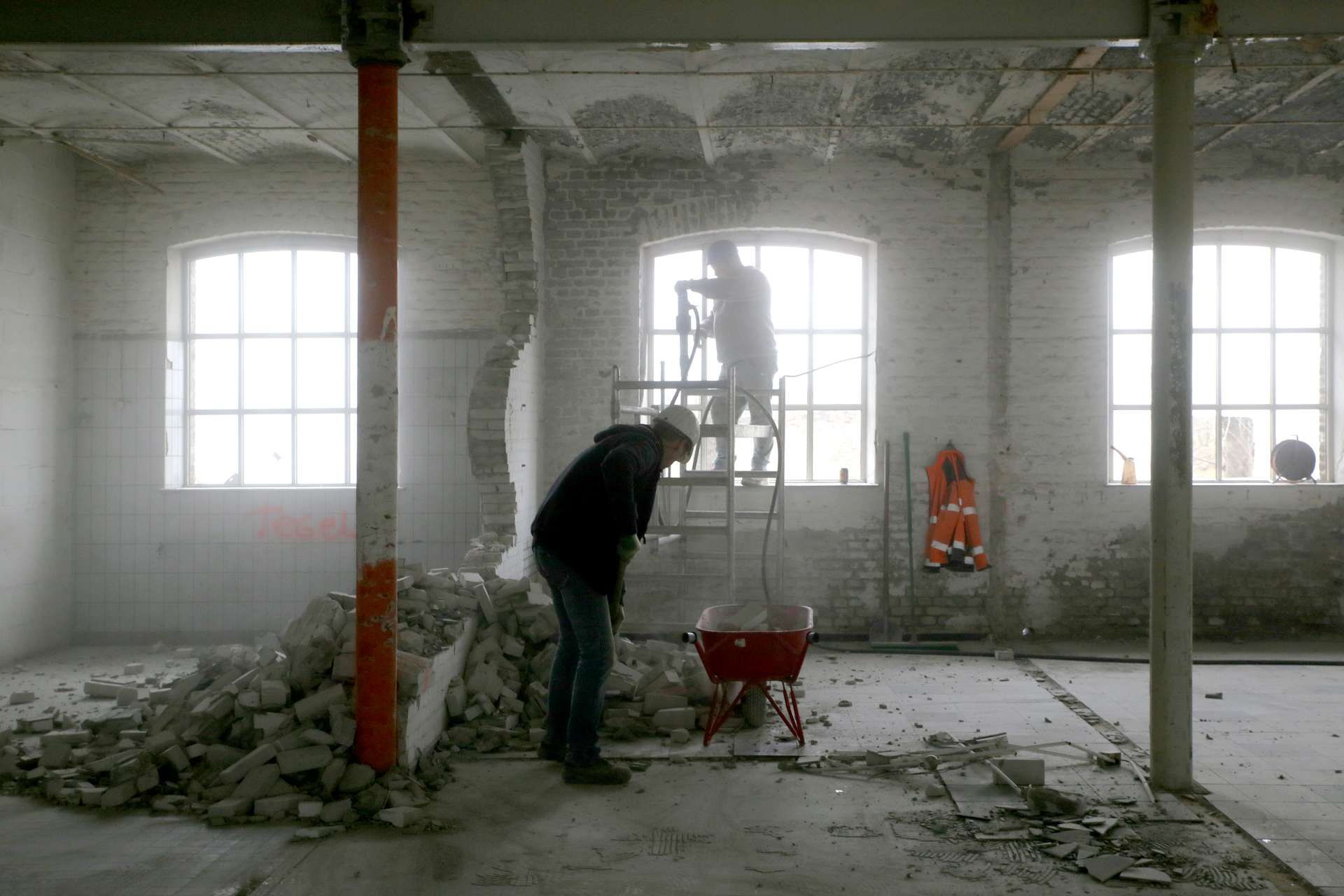 Bouwvakkers aan het werk in lege donkere fabriek