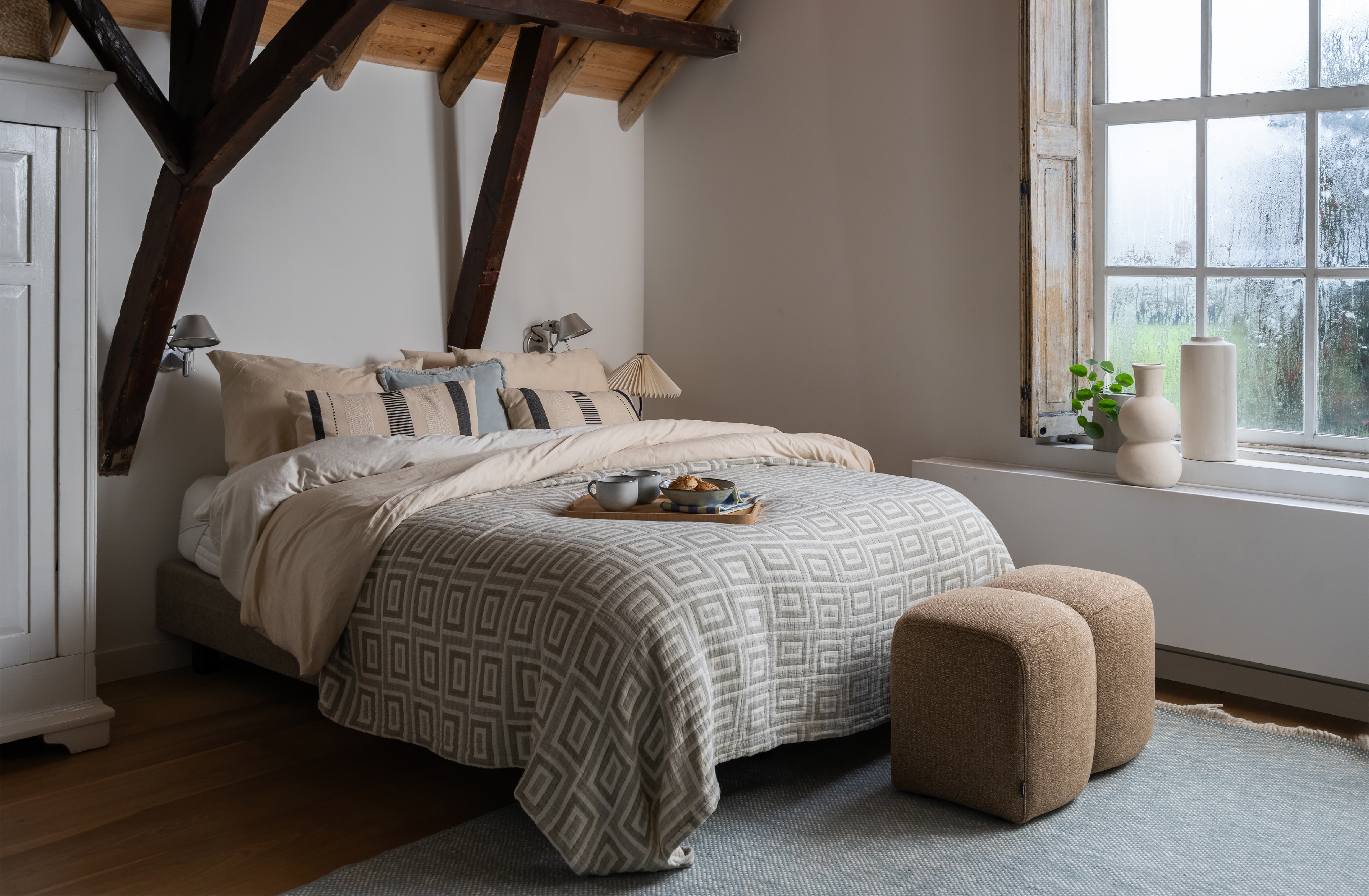 Landelijke slaapkamer met veel kussen en bedsprei met print