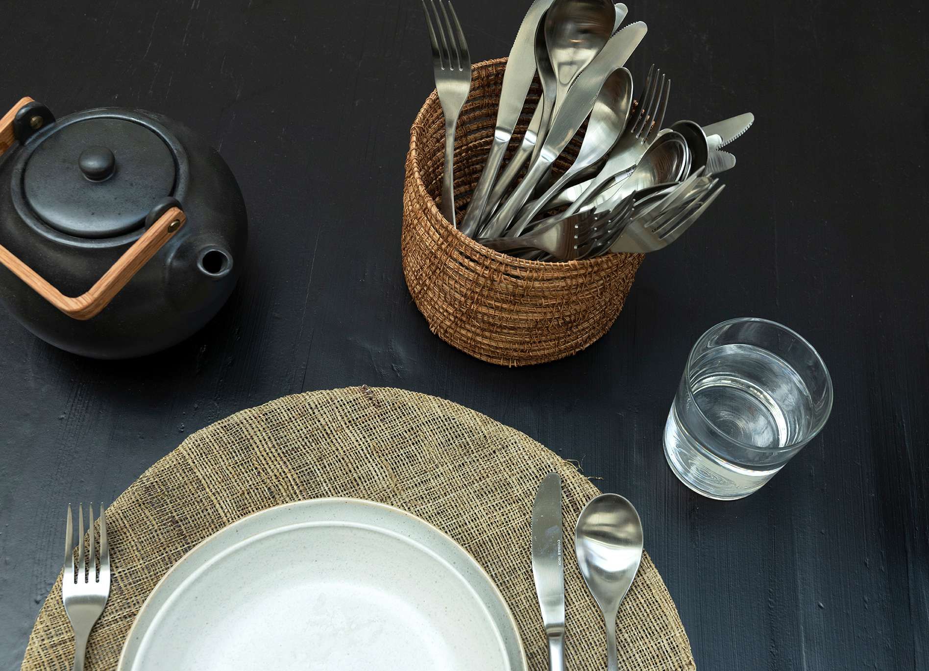 Zwarte eettafel met een ronde pot met zilver bestek erin