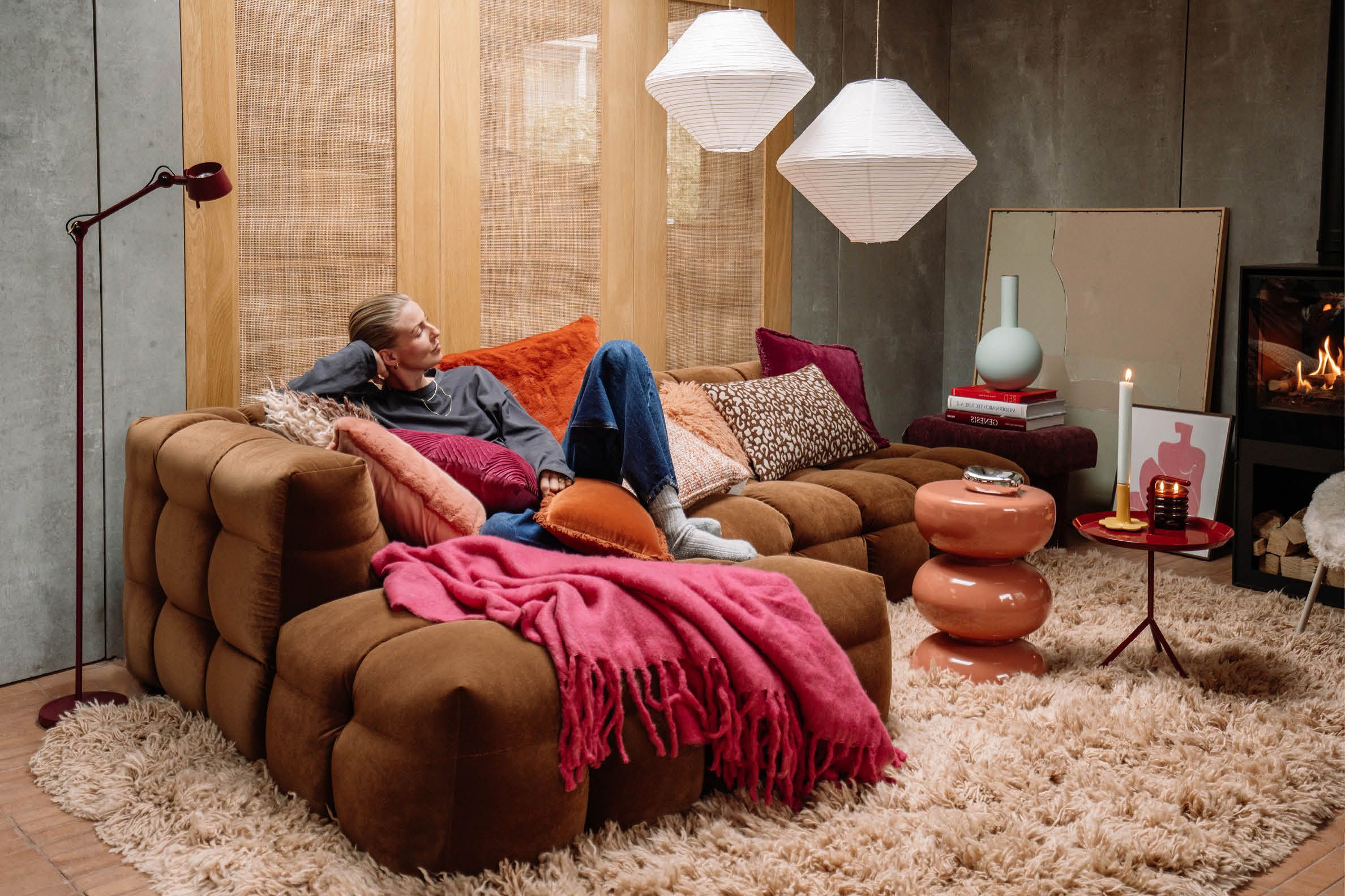 Gezellige woonkamer met bruine bank en roze en oranje woonaccessoires