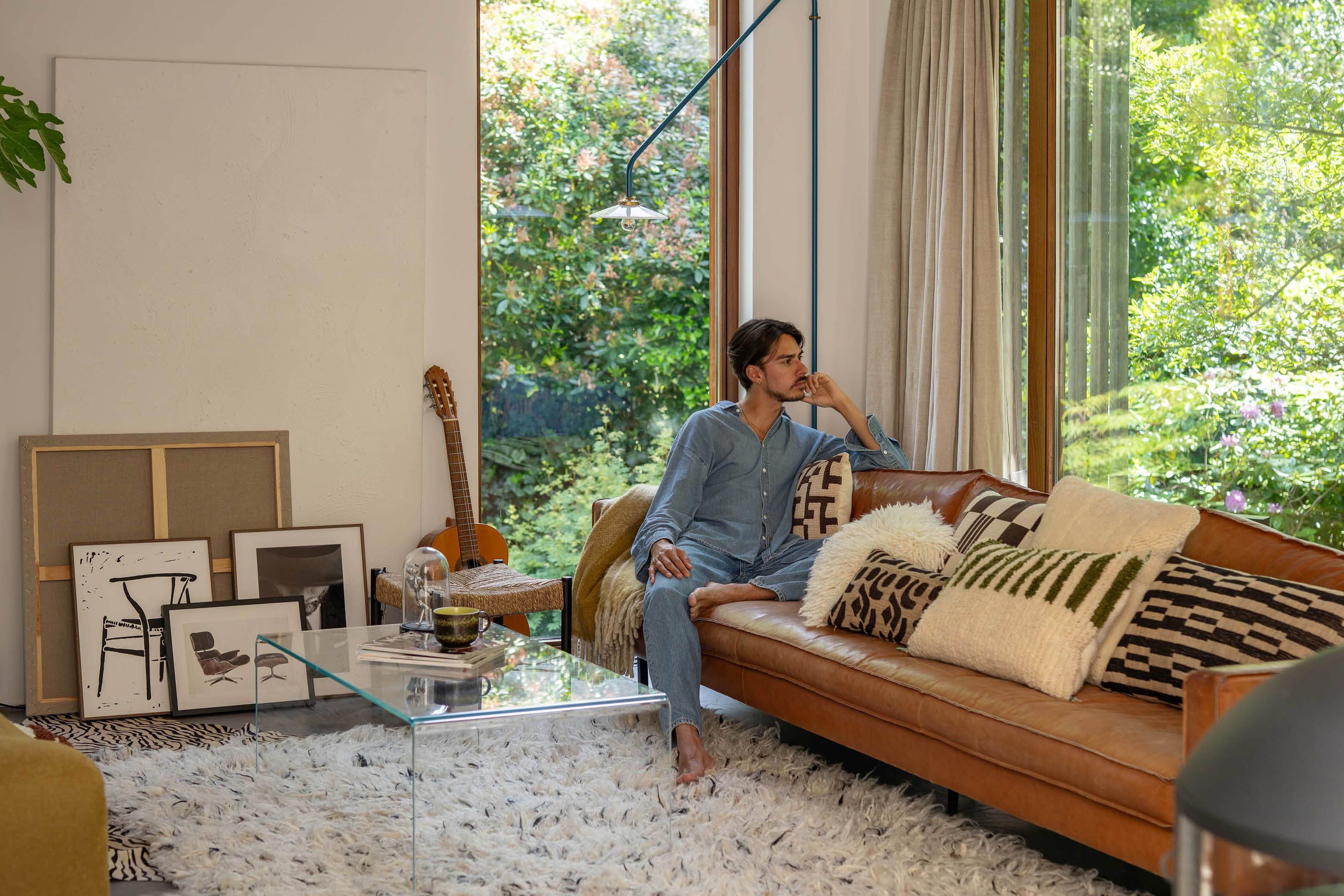 Man zit op cognac leren bank met wit wollig vloerkleed
